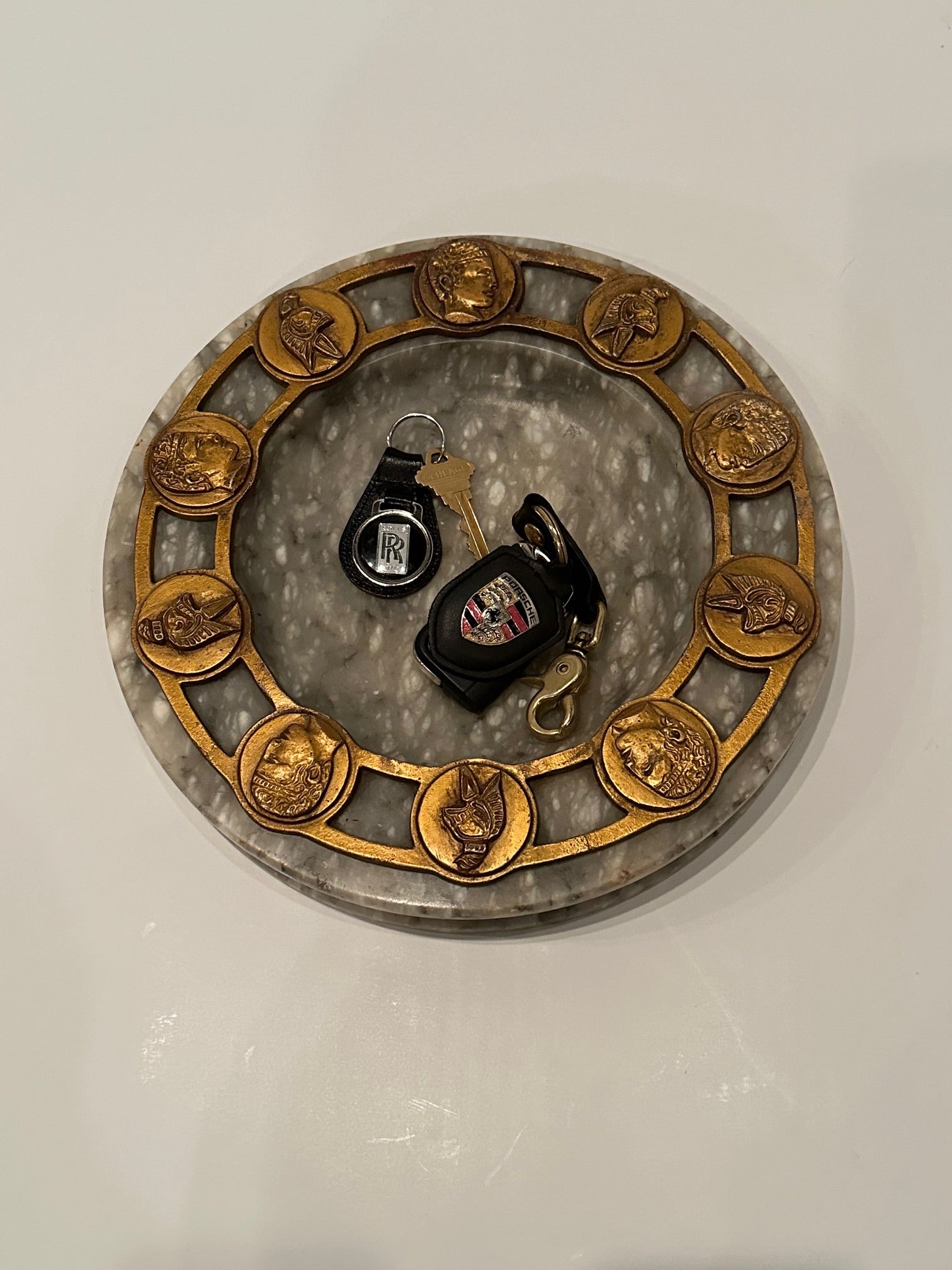 Super stylish round marble ashtray having Neoclassical Roman motif decoration in gilt metal around the periphery.  Great resting spot for your keys!