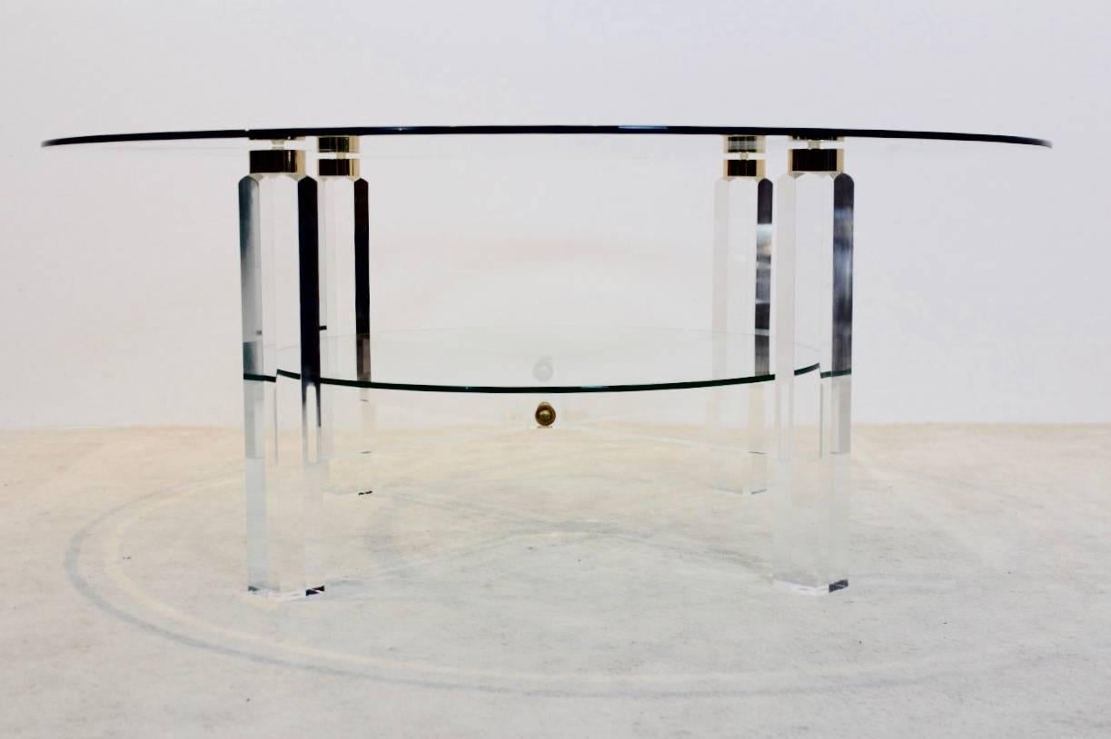 Stunning Belgian coffee table with glamorous performance. The light and glossy Lucite base with beautiful Brass accents has two-tier glass. The table is a unique example of the Hollywood Regency style and in excellent condition.