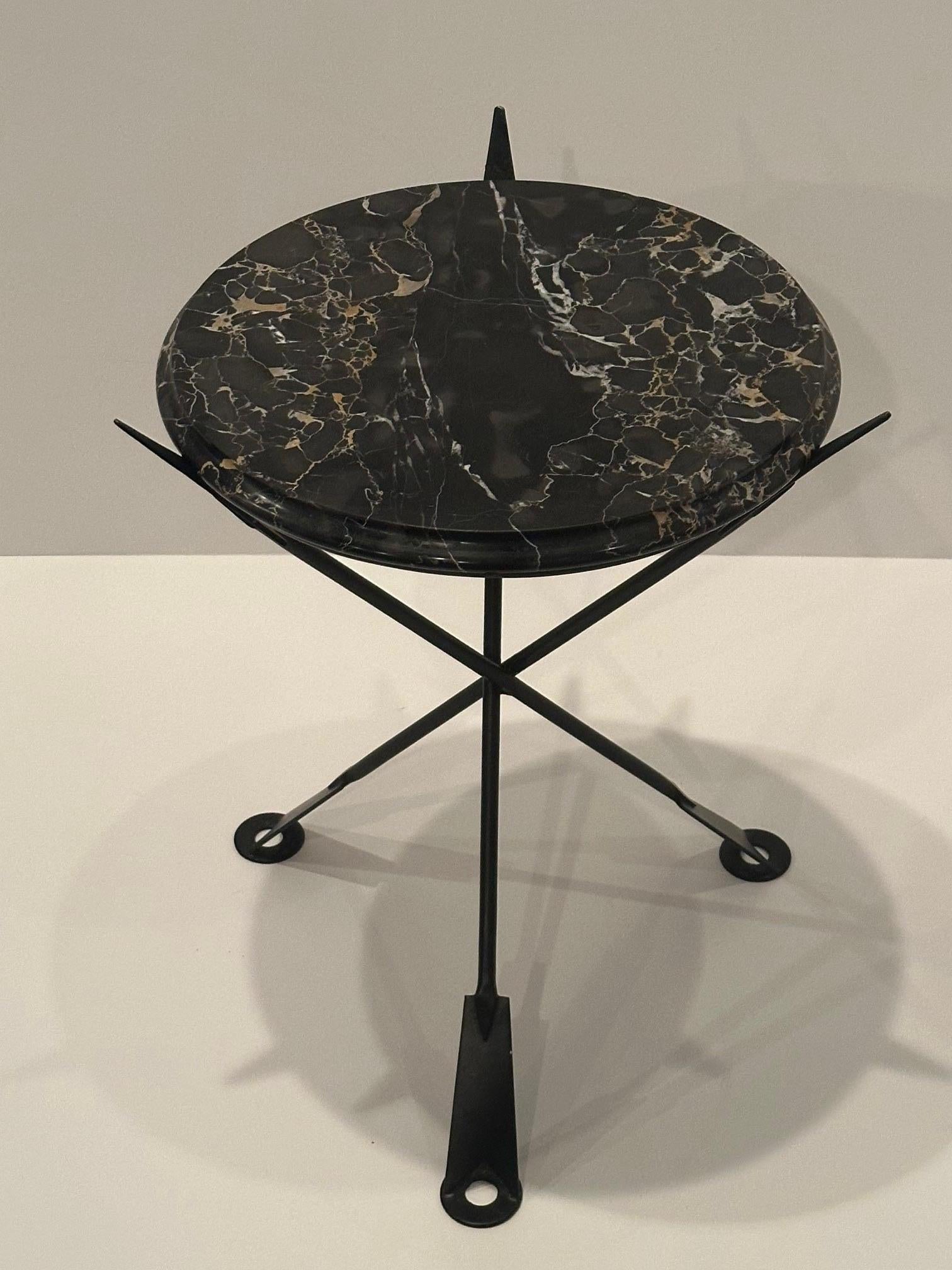 Glamorous round arrow motif painted iron side table with black and white marble top.
16