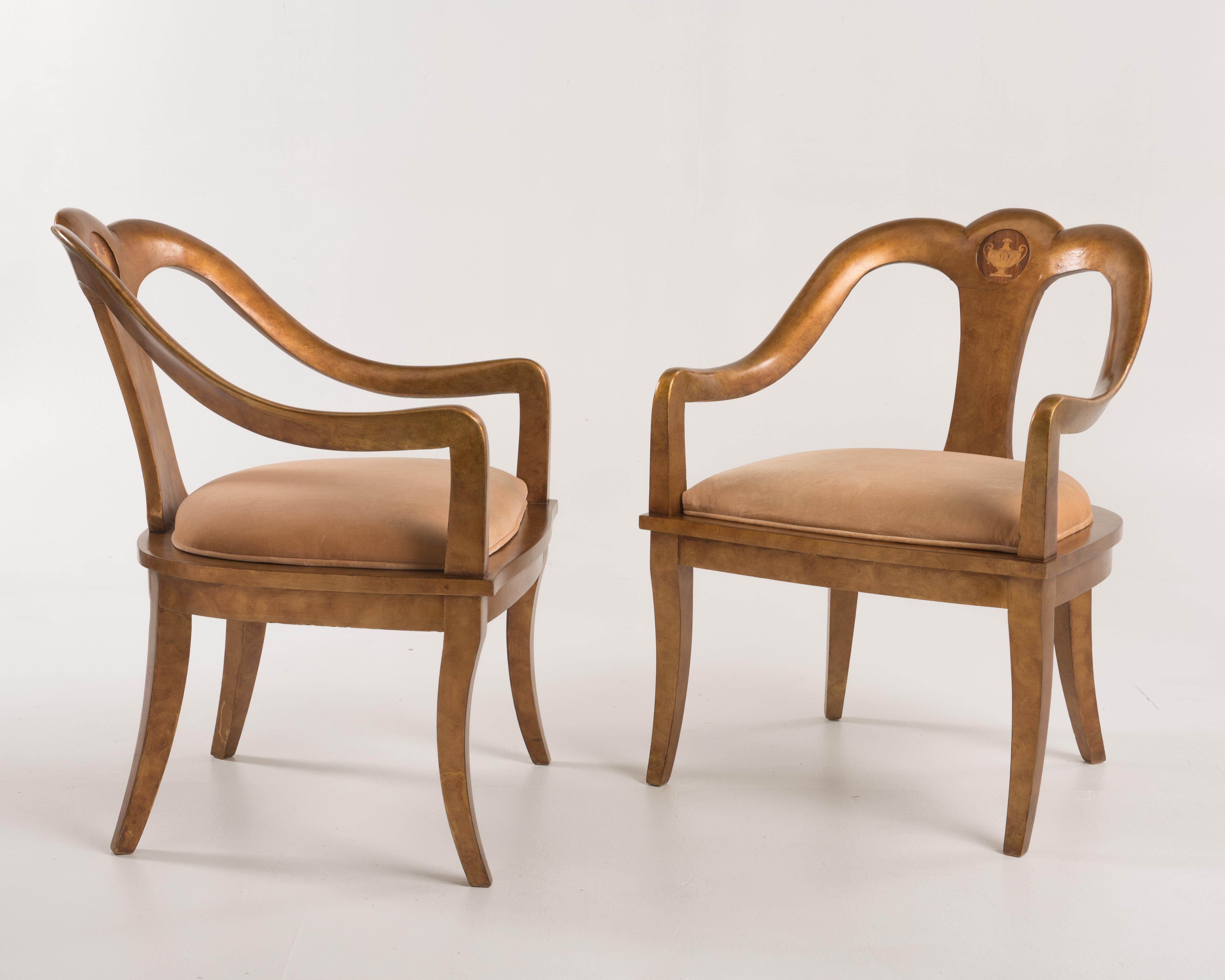 A pair of antique spoon back or Roman armchairs in a mottled gold finish. The chairs have a wonderful gold finish, cane seats and a center medallion with an urn inlay.