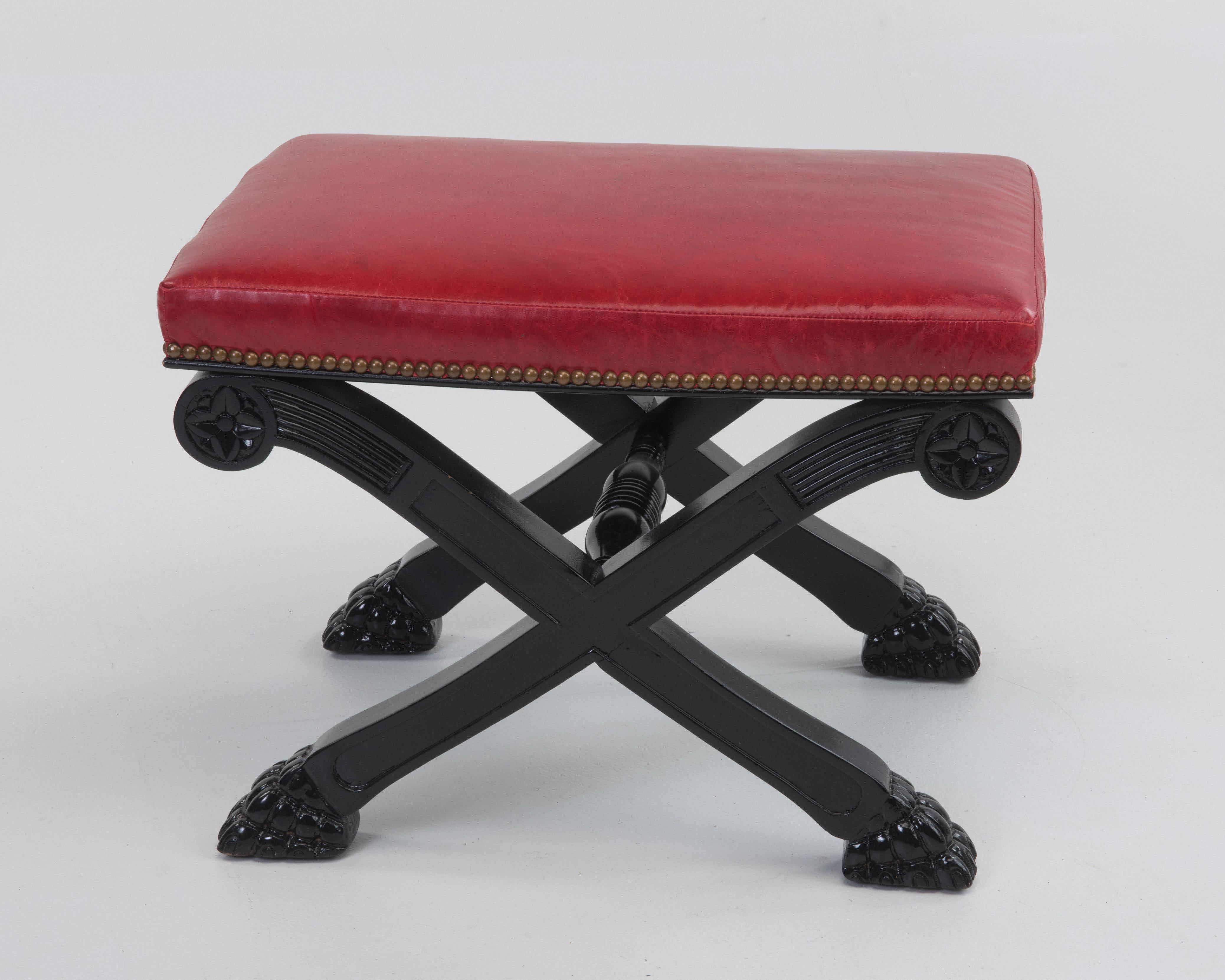 Sassy pair of newly upholstered red leather Hollywood Regency benches having ebonized X motife bases with paw feet. Brass nailheads give a polished finish.