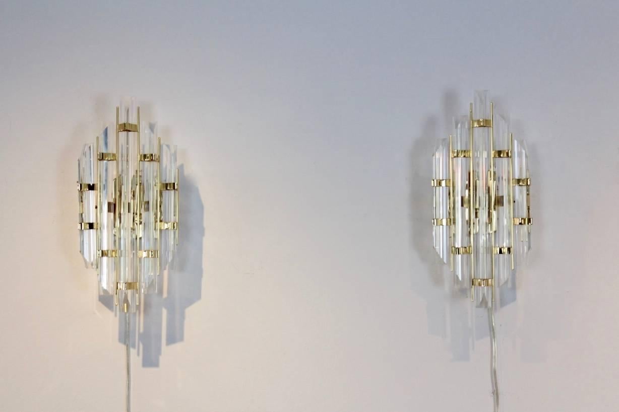 Highly sophisticated pair of brass and Murano glass sconces produced in Italy in the style of Venini the 1980s. Each lamp has a handsome brass back plate and has a beautiful geometrical pattern with five full glass Murano glass pieces. The beautiful