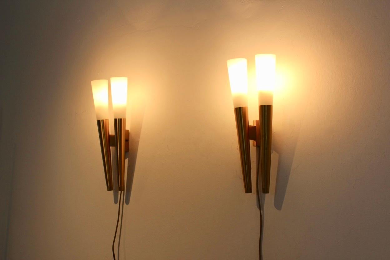 Rare and sophisticated pair of Italian wall sconces. Each lamp has a handsome Brass frame where the milky glass fits perfectly in, and each lamp comes with two lights for E14 light bulbs. The sconce has the style of a tourch and has very