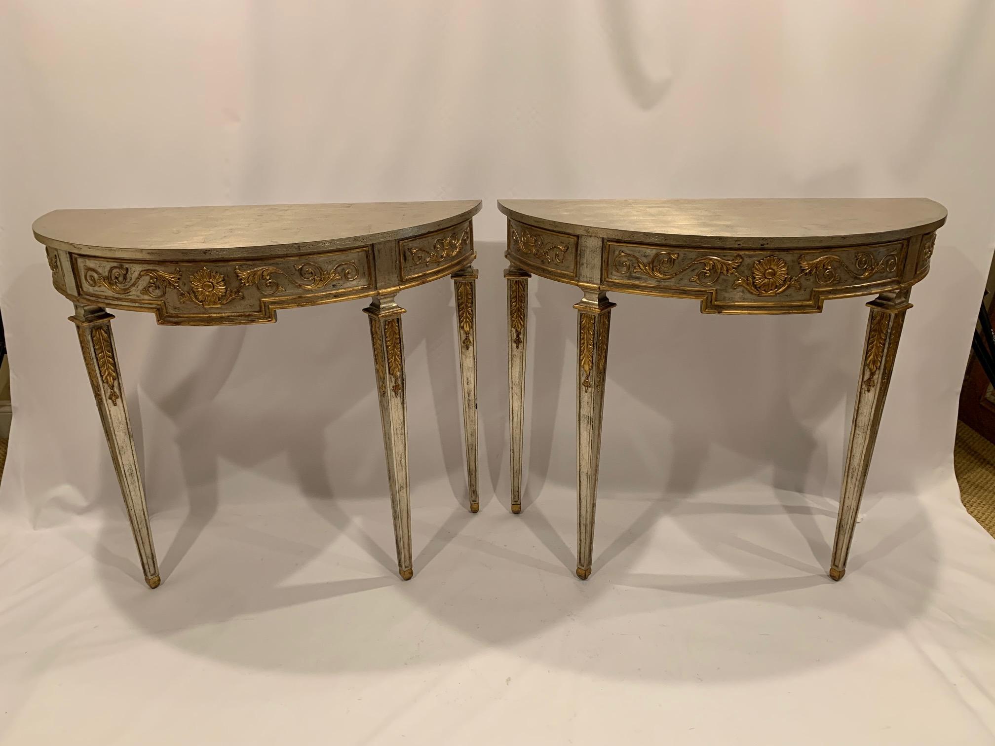 A very glamorous pretty pair of silver leaf carved wood demilune consoles having splendid gold gilded details.  The silver and gold leaf compliment eachother magnificently.