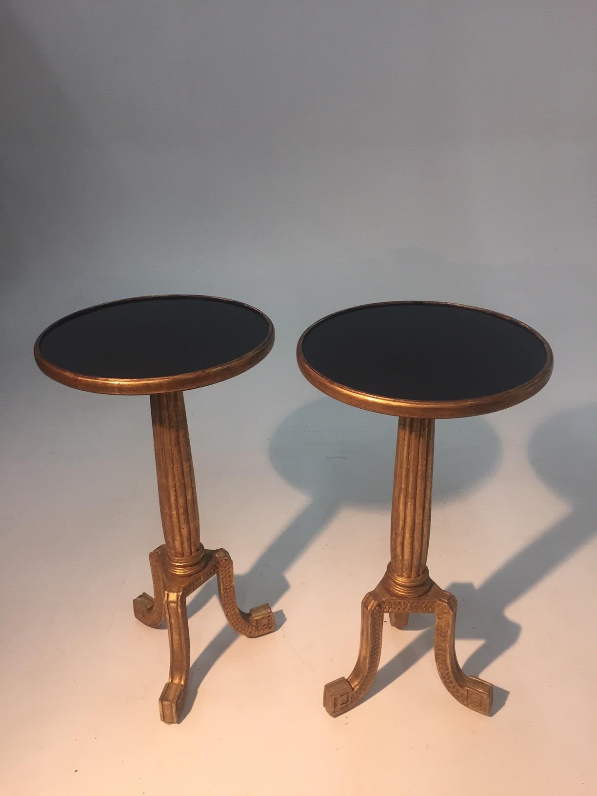 A glam pair of round end tables having giltwood fluted columns and tripod cabriole legs with glossy black crackled or aged circular surfaces.  By Dessin Fournic