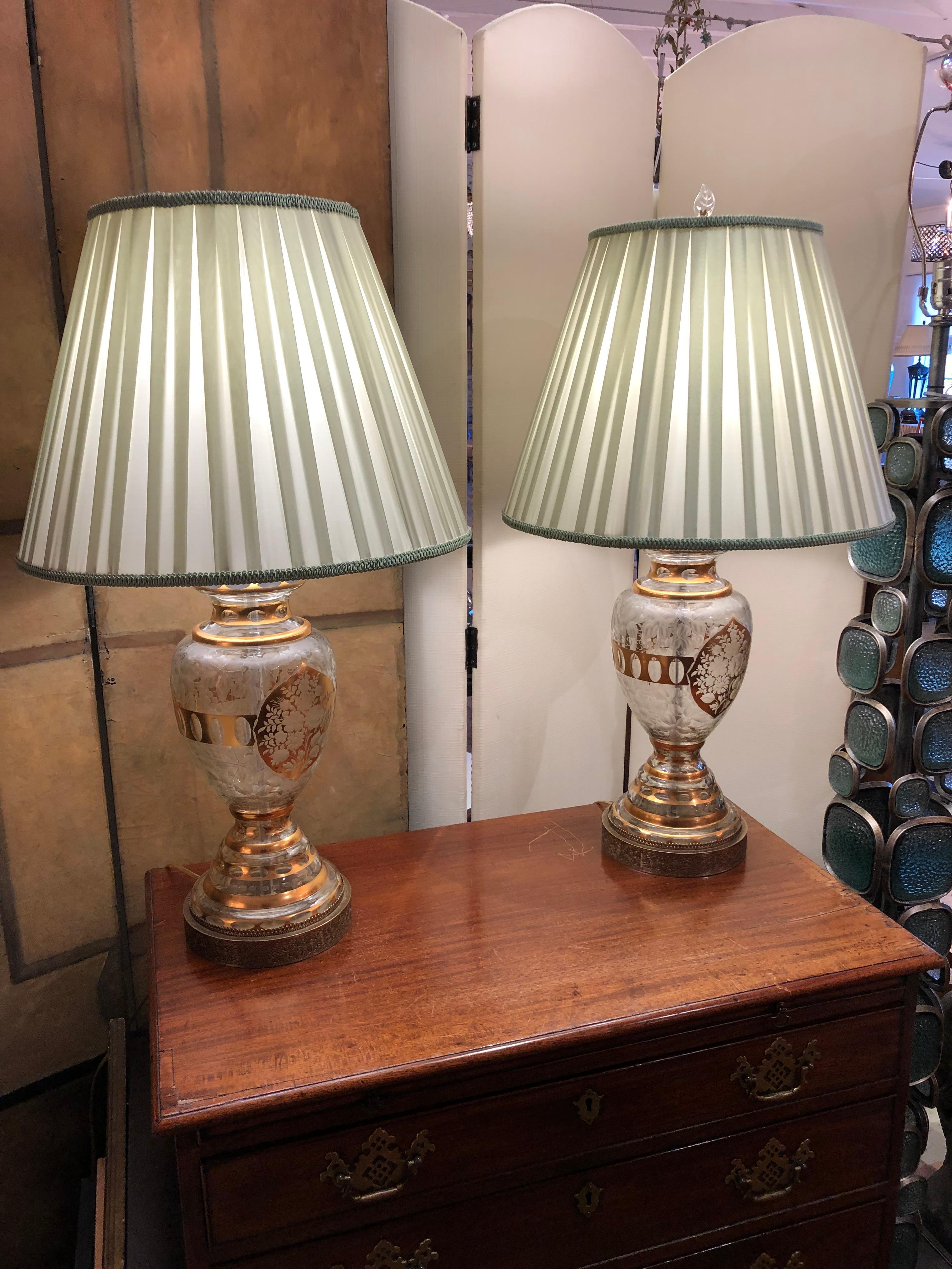 Impressive glamorous vintage crystal and metal lamps having ornate decoration, gilding on the crystal, and etched metal bases. Silk vintage shades included.
Measures: Base of lamp 7” diameter 
Shade: bottom 19” Diameter 13.75” High.