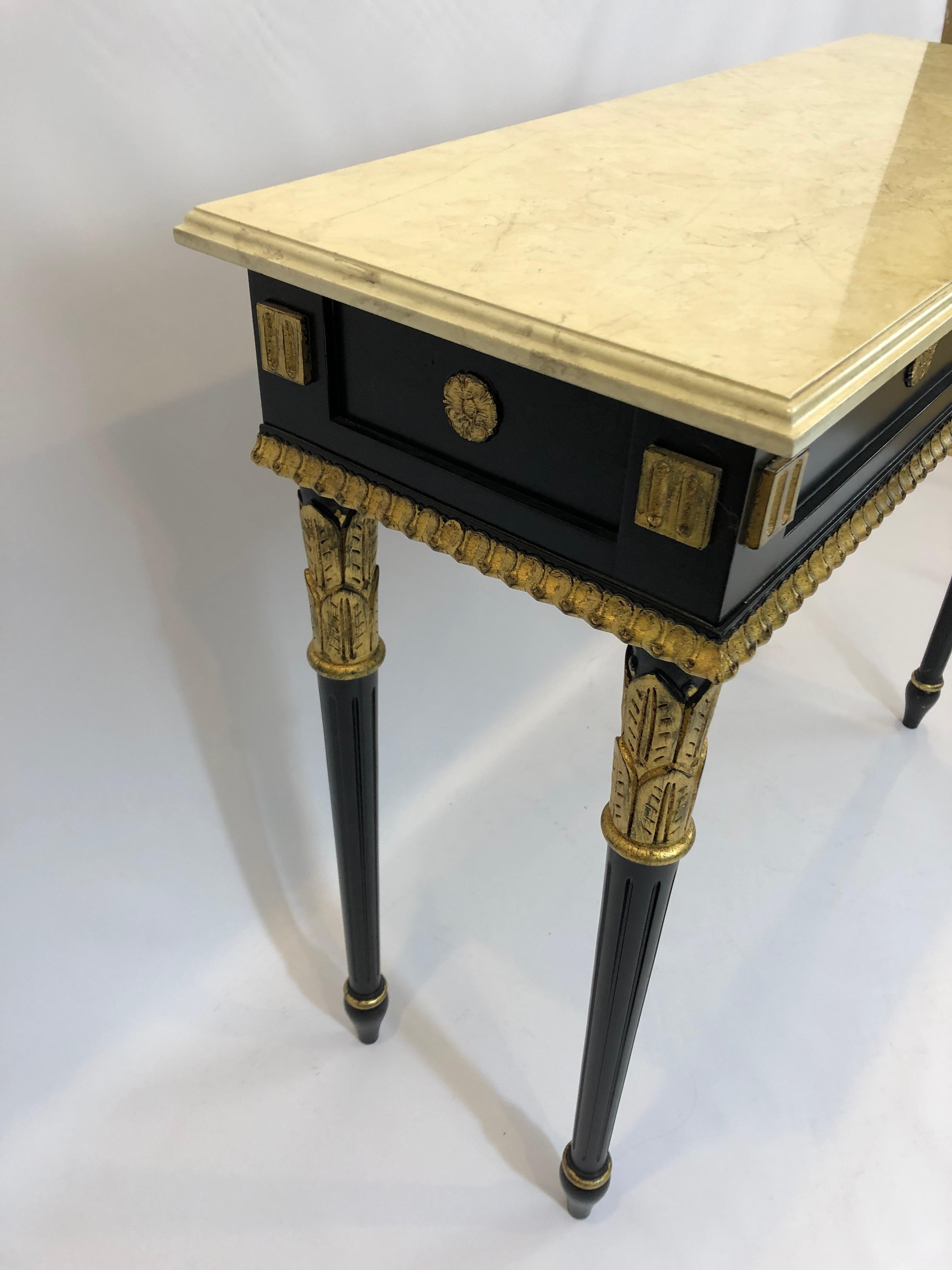 Glamorous Regency style small console table having an ebonized base with beautiful gilded decoration, with off-white faux marble top.