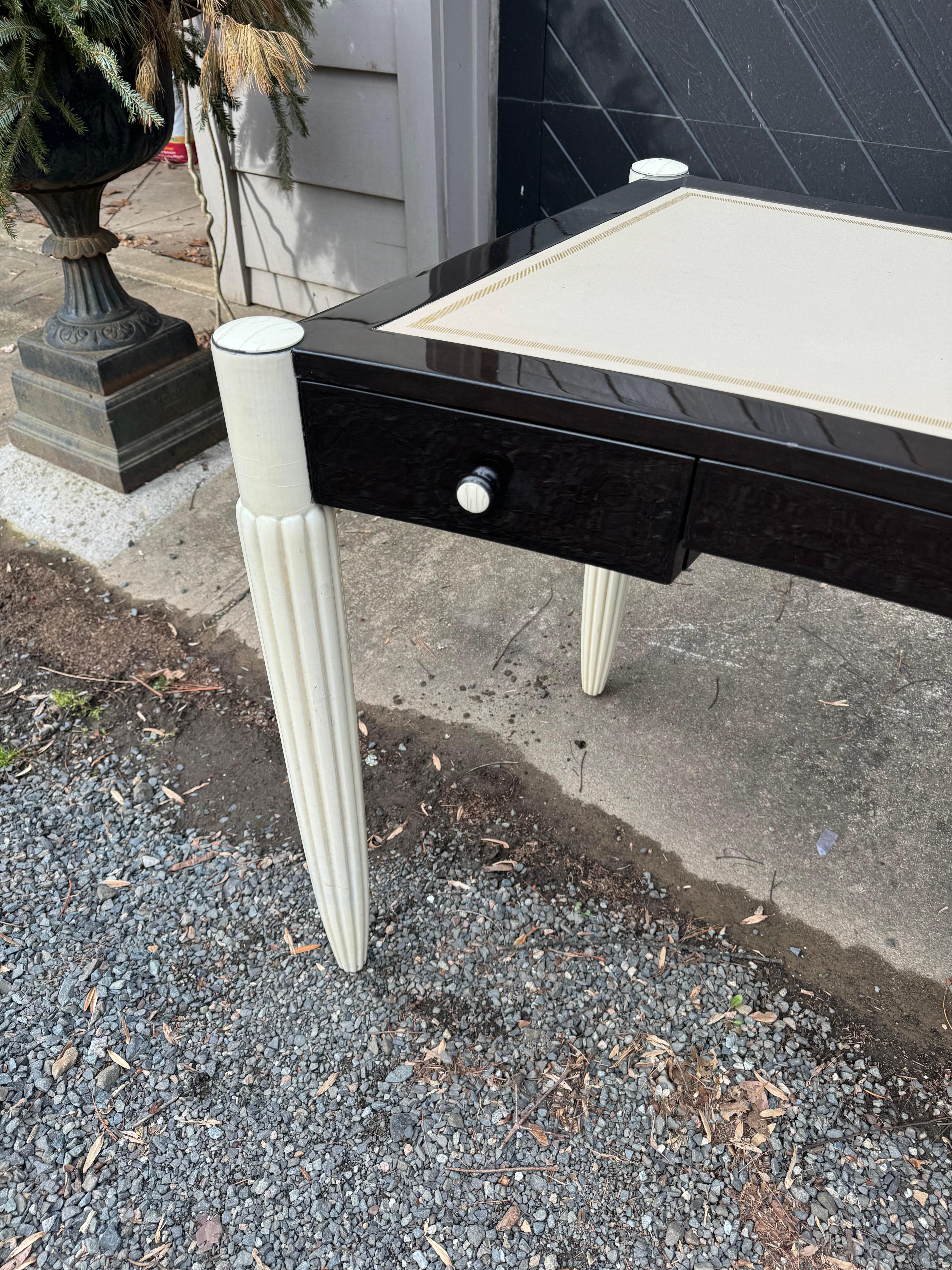 Super chic designer desk by Sally Sirkin for J. Robert Scott, know as the Paris desk.  There are ribbed and tapered legs and a black and ivory enamel finish.  The corner, knobs and keyhole have a faux bone appearance and the leather top is ivory