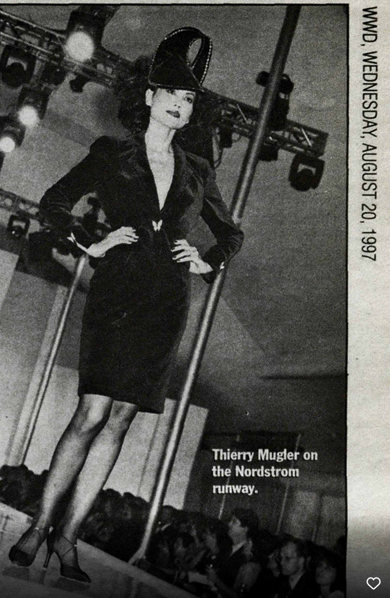 Questo bellissimo ensemble di Thierry Mugler arriva come una scossa di elettricità! Tagliato da un sontuoso velluto rosso che si beve la luce, il tailleur con gonna è un classico di Mugler: una silhouette architettonica che scolpisce il corpo in una