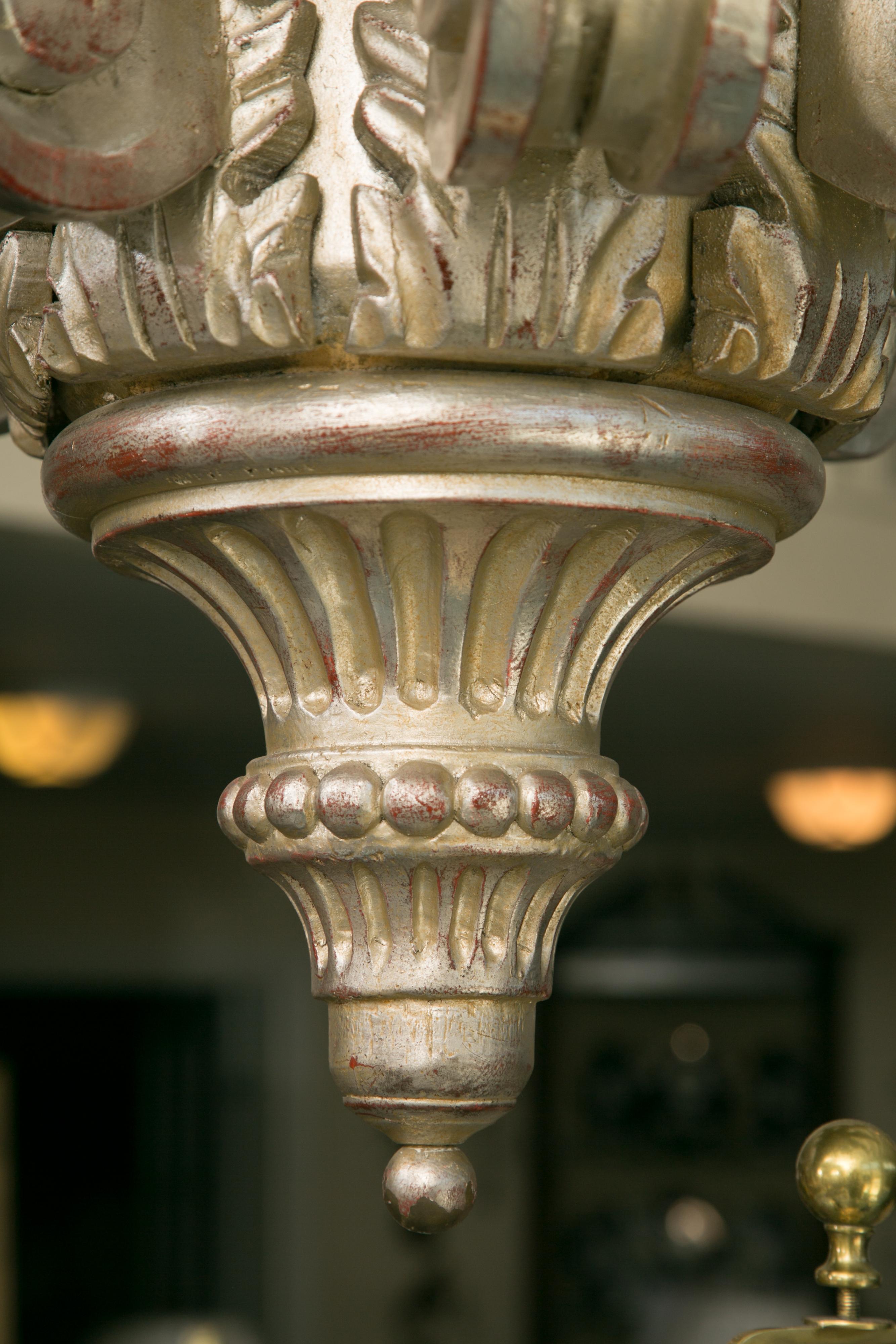 This is an impressive hand-carved and silver leafed twelve light electrified hanging light fixture.