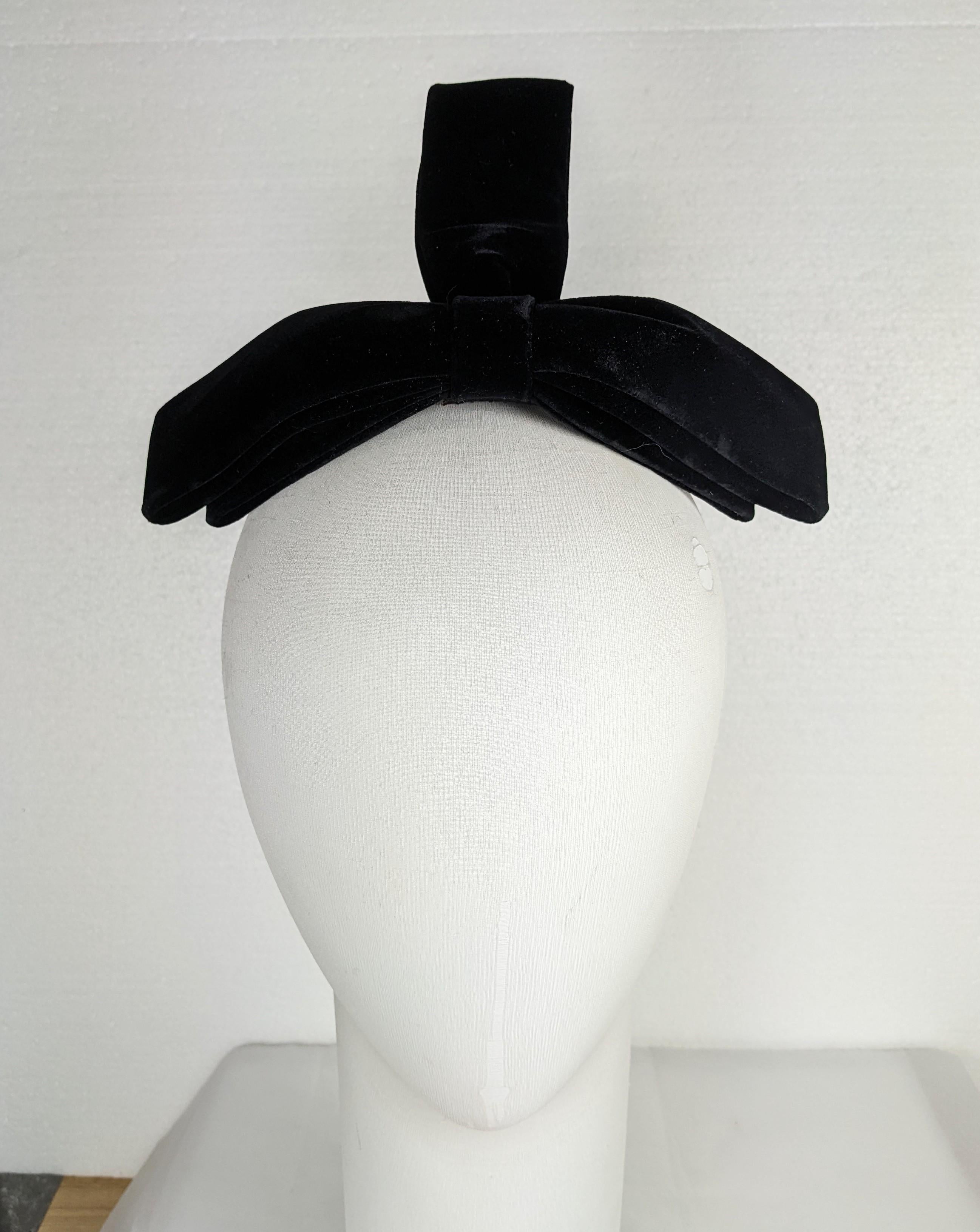 Fiocco di velluto glamour per capelli degli anni '60. Il velluto di cotone nero irrigidito è formato da un fiocco a tre punte con cinturino posteriore e pettine nascosto. Progettato per capelli sciolti all'indietro per i tuoi momenti più eleganti.