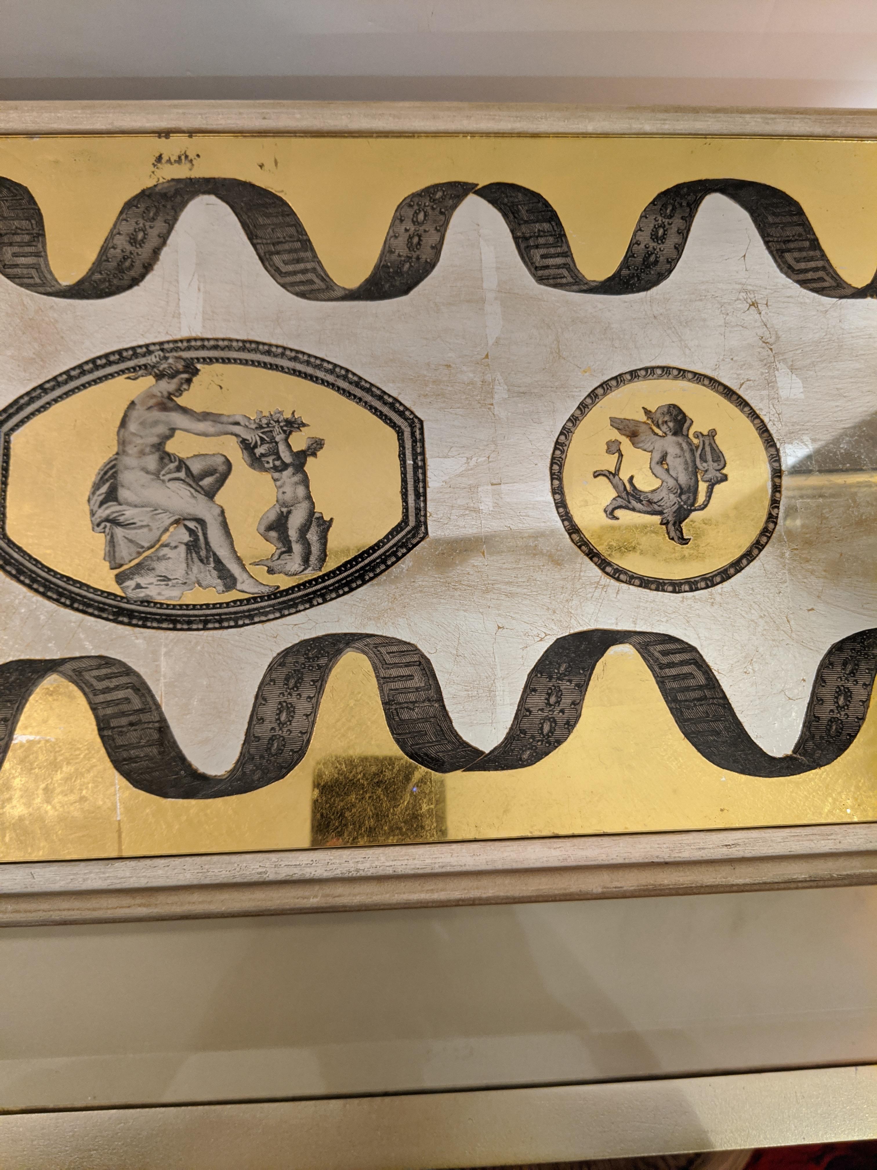 An eye-catching gorgeous vintage Églomisé rectangular lidded box with mirrored compartmentalized interior. The exterior decoration in yellow, black and mirror has romantic putti and figures.