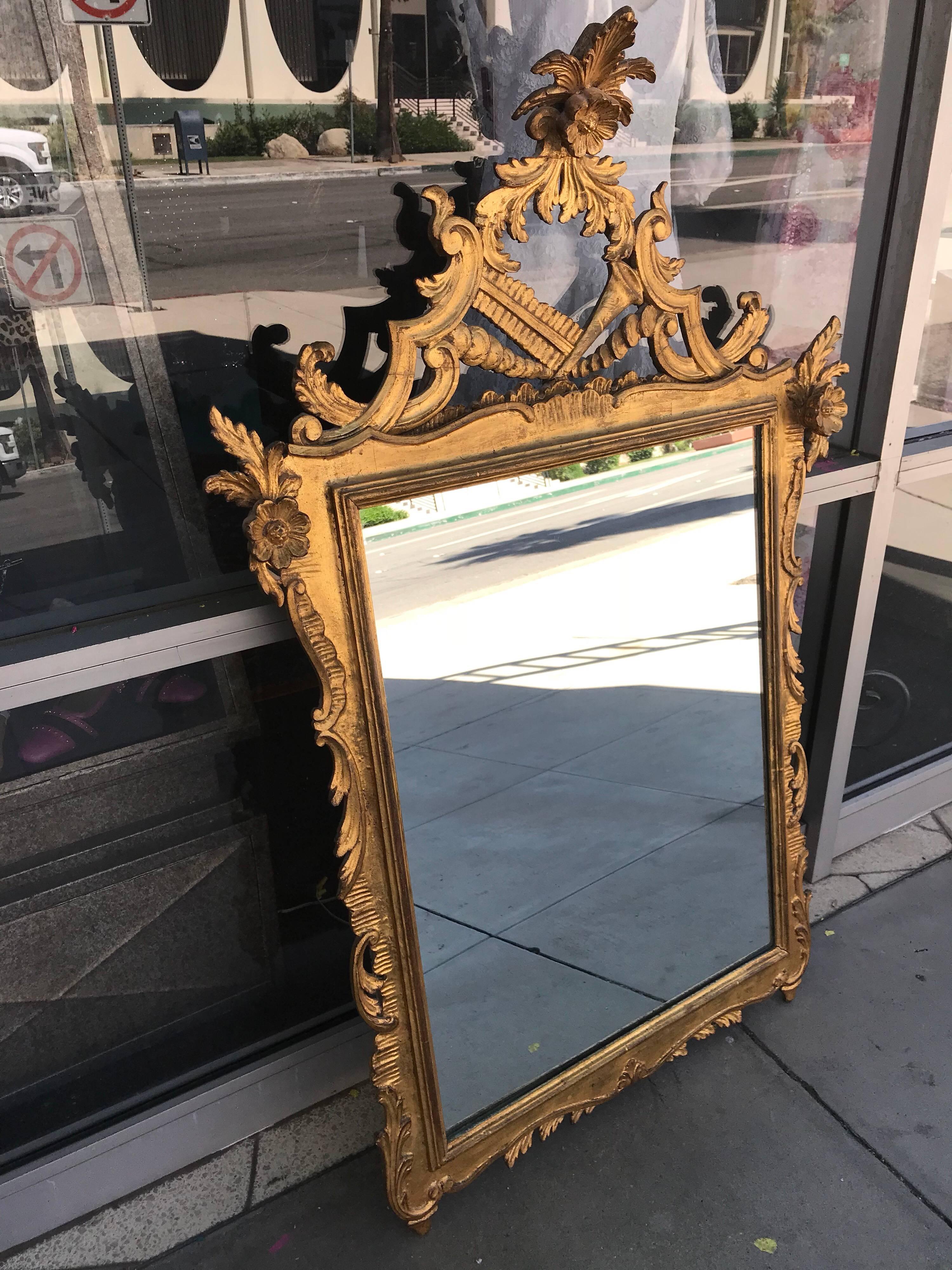 This is a very high end vintage mirror, made in the 1950s. Beautifully detailed in gold, the mirror is solid wood construction. From a very chic Palm Springs estate. Looks like the crown of mirror has been repaired previously. Not easily noticeable. 