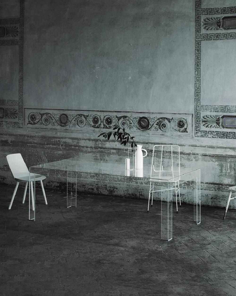 Series of high tables obtained by glued 8 mm thick tempered glass plates, cut with water jet and with 45° chamfered edge. Available in extralight transparent glass, glossy lacquered. The formal purity, the sobriety and the sophisticated