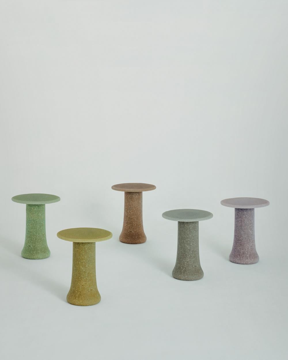 Serie de mesas redondas altas y bajas, fabricadas con un conglomerado especial de 
Granalla y fragmentos de vidrio 100% reciclados. Cada pieza está hecha a mano 
y se caracteriza por una superficie y una geometría irregulares, con una 
aspecto