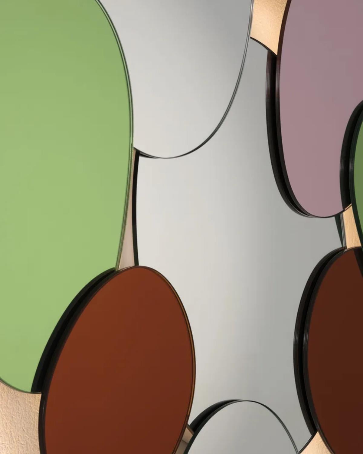 Composizione murale composta da 10 specchi ovoidali irregolari, di forme, dimensioni e colori diversi, parzialmente sovrapposti e fissati l'uno all'altro. Un pannello con ganci multipli permette di appendere lo specchio e di orientarlo in qualsiasi