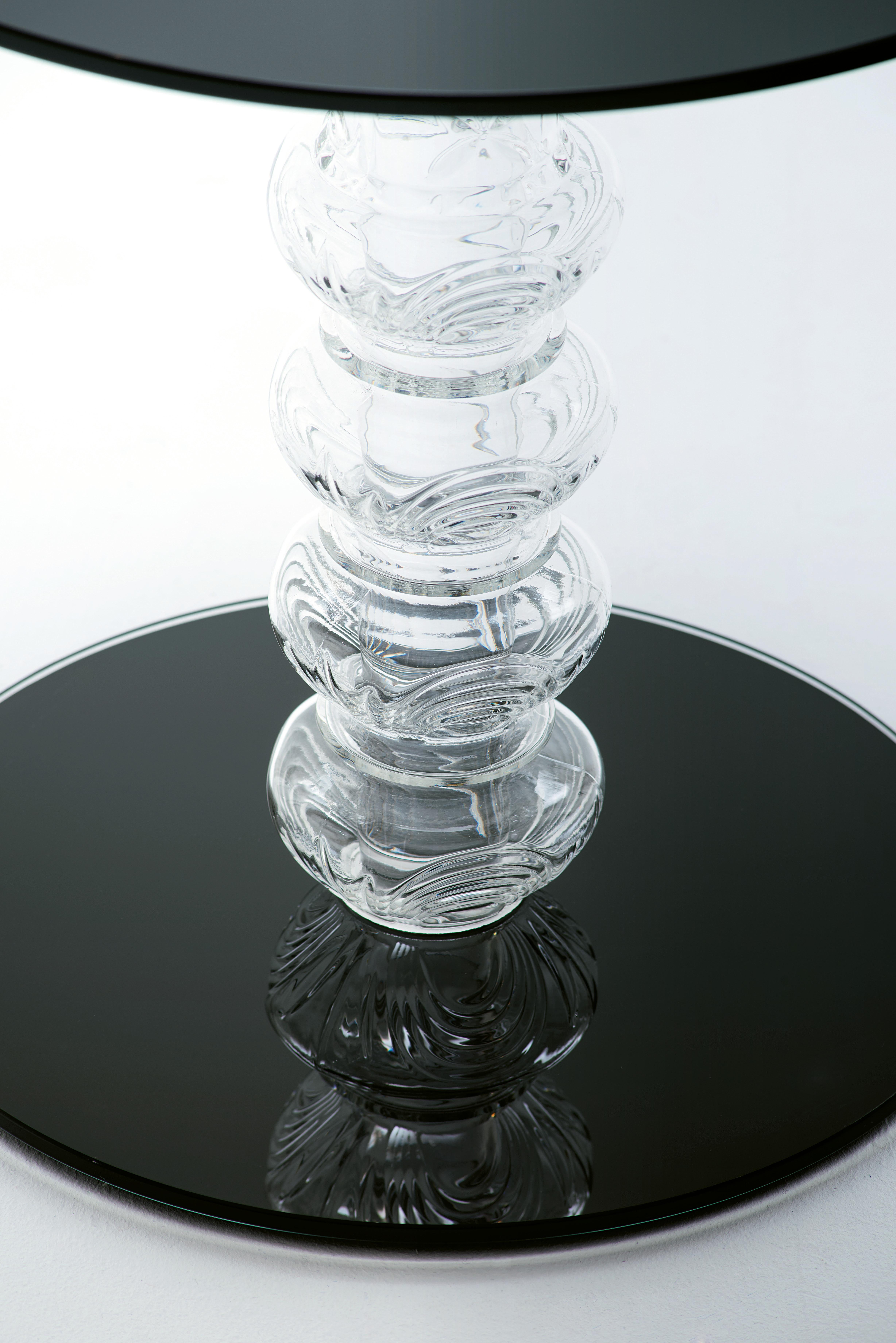 Mesas bajas redondas disponibles en dos alturas con tablero y pie de cristal templado lacado brillante de 8 mm de grosor. La base es de vidrio soplado moldeado, con decoraciones grabadas en la superficie.

Acabados disponibles: Cristal lacado