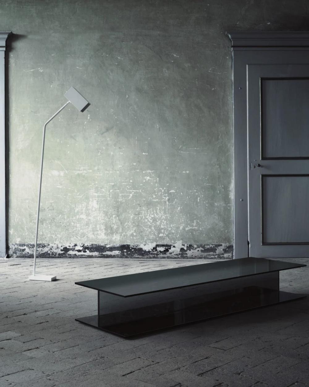 Collections composed of low tables and benches, obtained by gluing together three slabs of smoked glass, so that they look like a joist. The top-seat and the base are in 12 mm thick tempered glass, whereas the vertical support is in laminated glass.