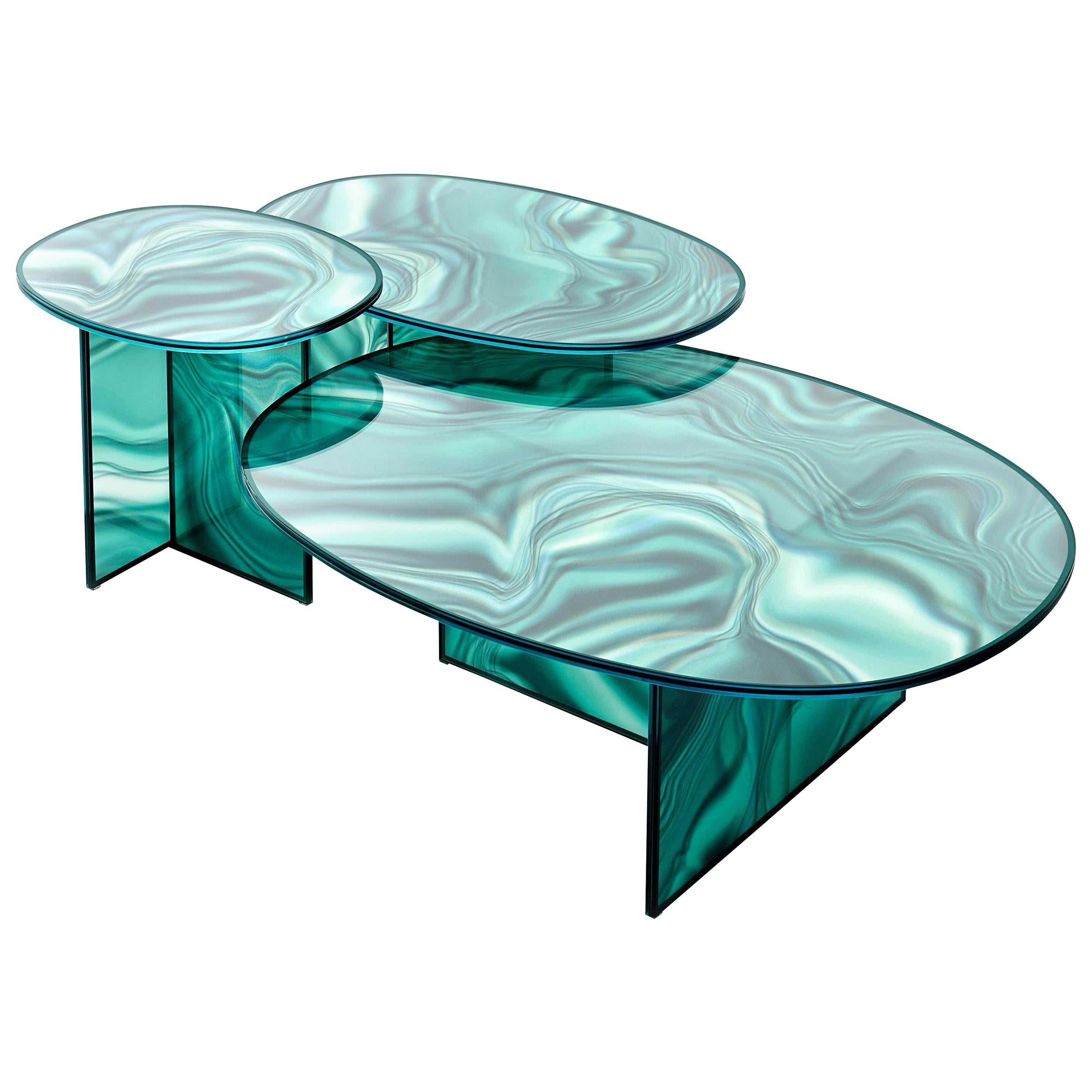 High and low oval-shaped tables in tempered extra light glass, with faded and irregular decoration which takes on the color and veins of marble.
The surprising image changing effect makes the veining look dynamic and variable depending on the