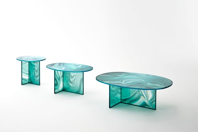 Set of high and low oval-shaped tables in tempered extra light glass, with faded and irregular decoration which takes on the color and veins of marble.
The surprising image changing effect makes the veining look dynamic and variable depending on