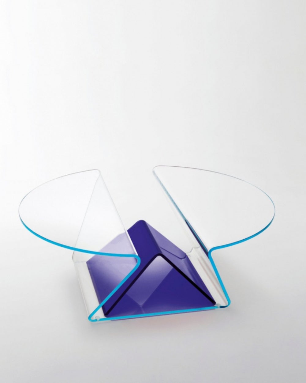 Mesa baja extremadamente funcional de aspecto ligero y formas suaves y delicadas en cristal extralight de 12 mm, moldeado y curvado gracias a un complejo proceso de curvado del cristal, obteniendo dos tableros en voladizo separados por un práctico