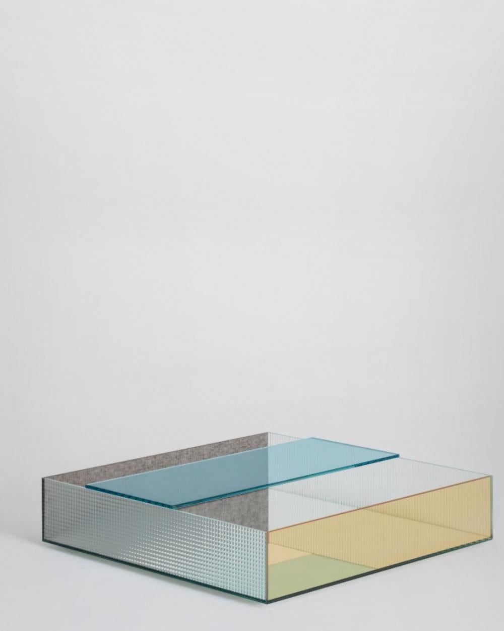 Sophisticated composite low table in shape of a tub, made by bonding 45 ° laminated glass slabs, different in quality and finish. The bottom is mirrored, whilst the four sides are made of the following materials: 520. Flutes, 523. Quadretti, 552.