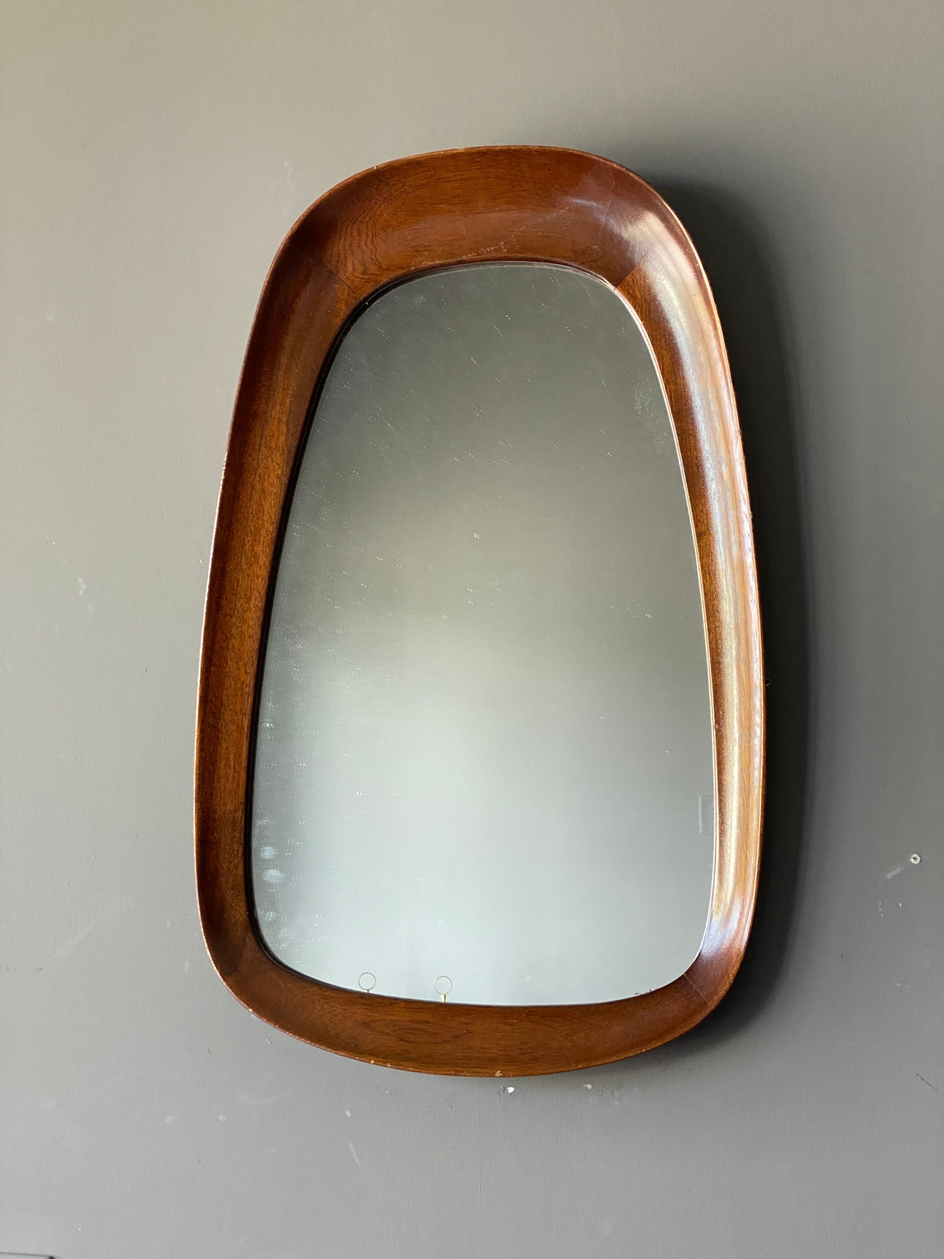 A rare organic wall mirror produced by AB Glas & Trä, Hovmantorp, Sweden. In sculpted teak and crystal mirror glass, labeled. 

Other designers of the period working in the organic style include Fontana Arte, Gio Ponti, and Paolo Buffa.
