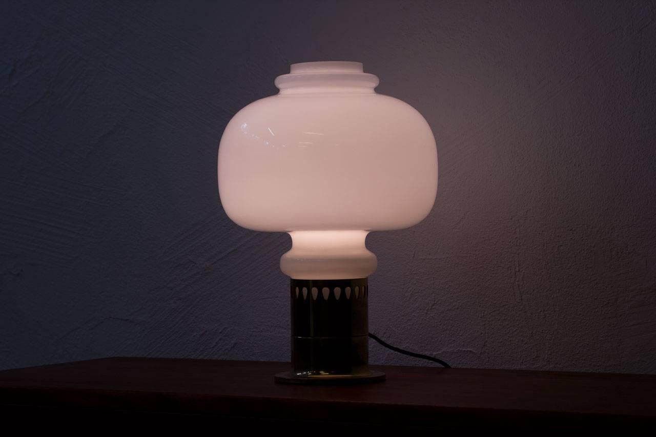 Table lamp designed by Hans–Agne Jakobsson. Designed in Sweden in the 1960s. Large white glass shade supported by a brass base. Light switch on cord.