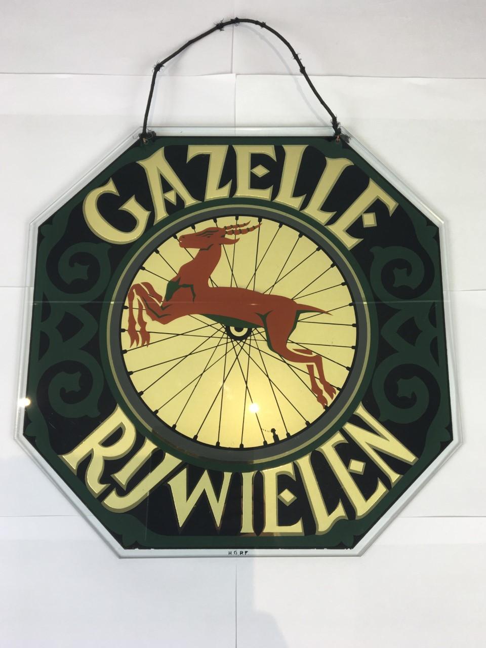 Old glass advertising sign for Gazelle Bicycles, a bicycle factory in the Netherlands since 1892. This Art Deco publicity sign is made of glass - advertising behind glass. 
Beautifull green with black design, golden lettering with in the middle a