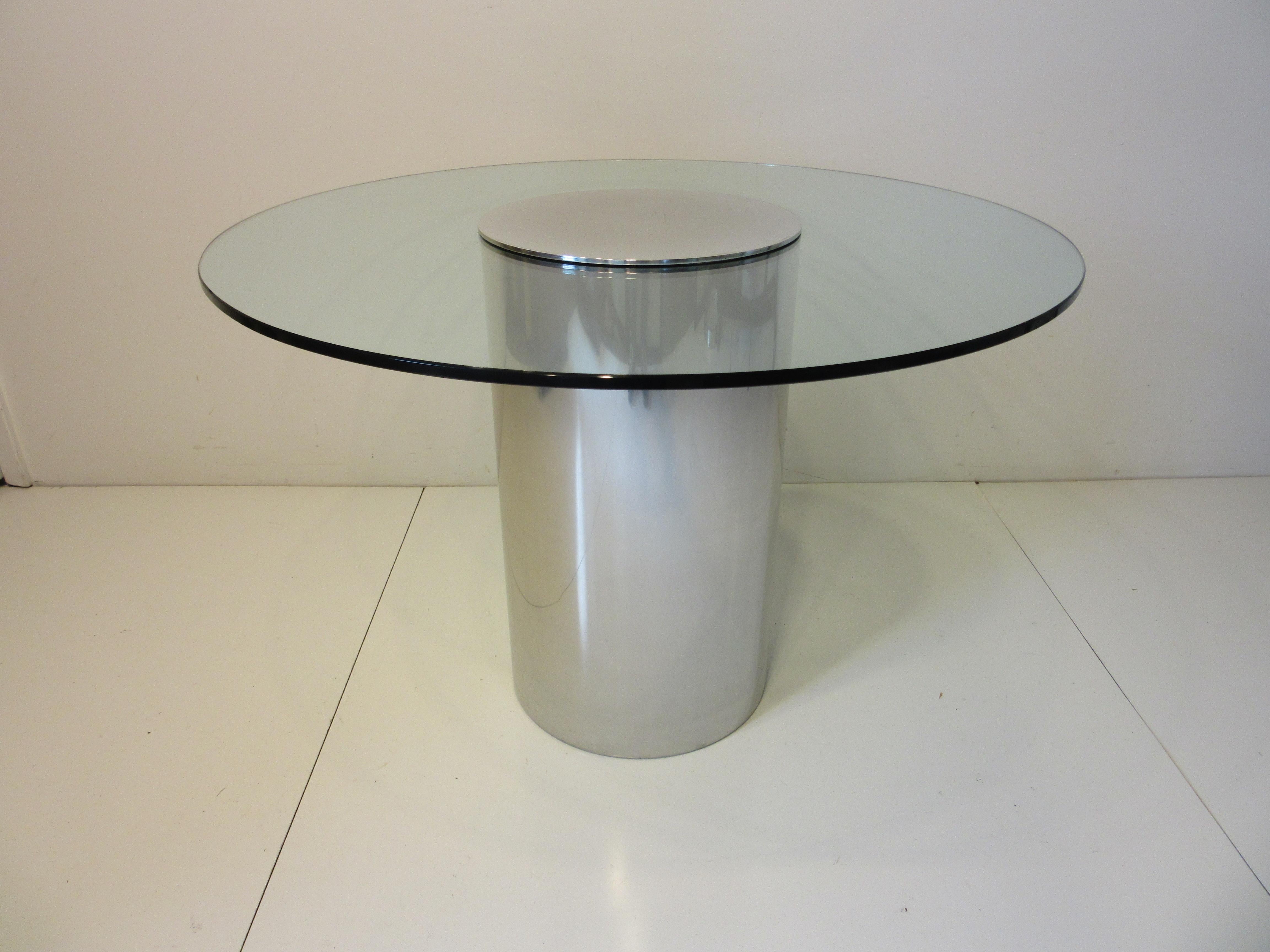 A plate glass topped café dining table with polished aluminum barrel tube base and cap in the manner of Leon Pace and the Pace Furniture company. A rich and simple design from the 1970's that can be used in a tight space eat in kitchen or as a game
