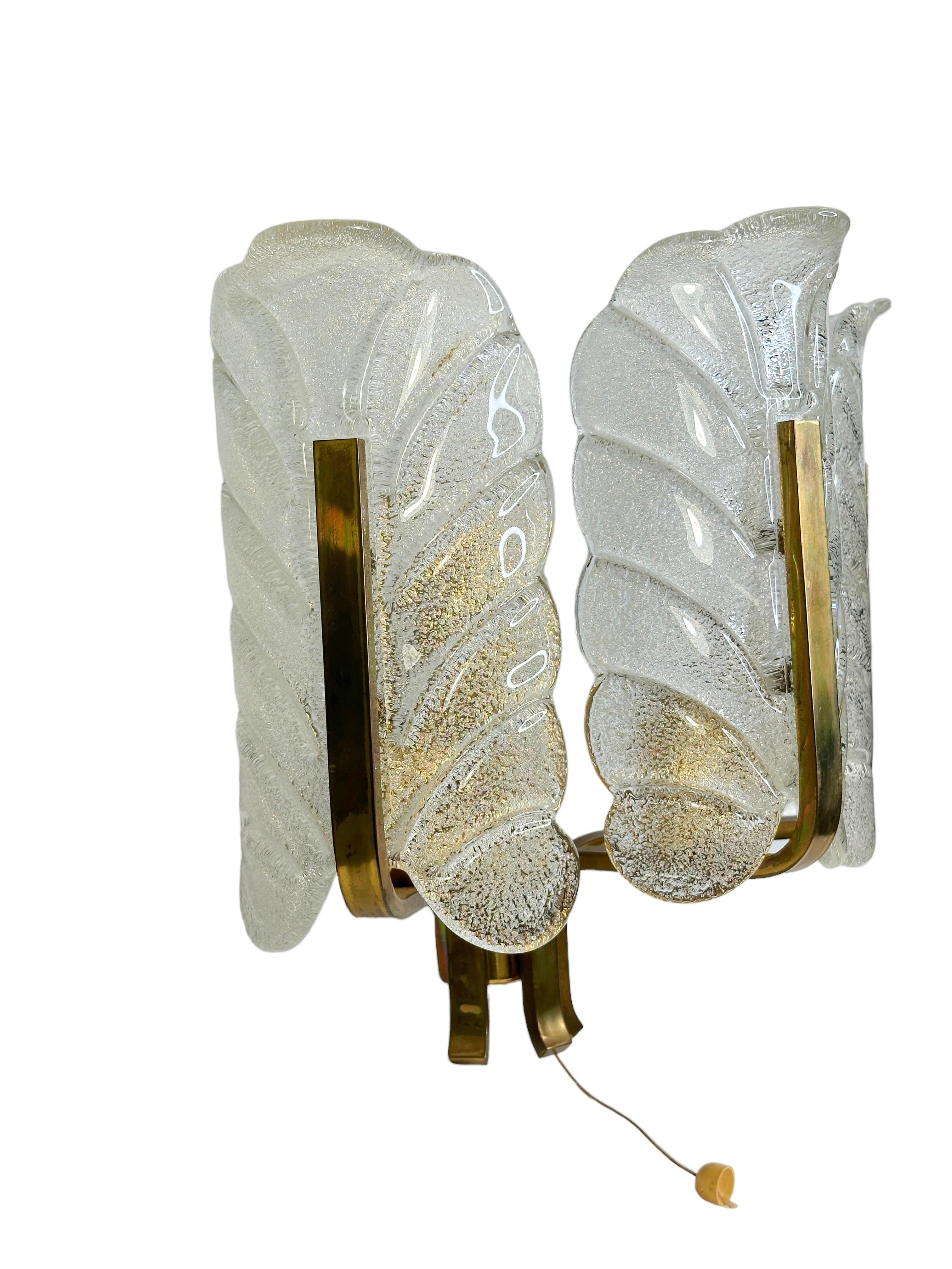 Large glass and brass sconce by Carl Fagerlund for Orrefors. This large brass wall light consists of two arms has two light sources. Each arm contains a Murano frosted glass acanthus leaf shade. Offered midcentury light has original wire.
Found at
