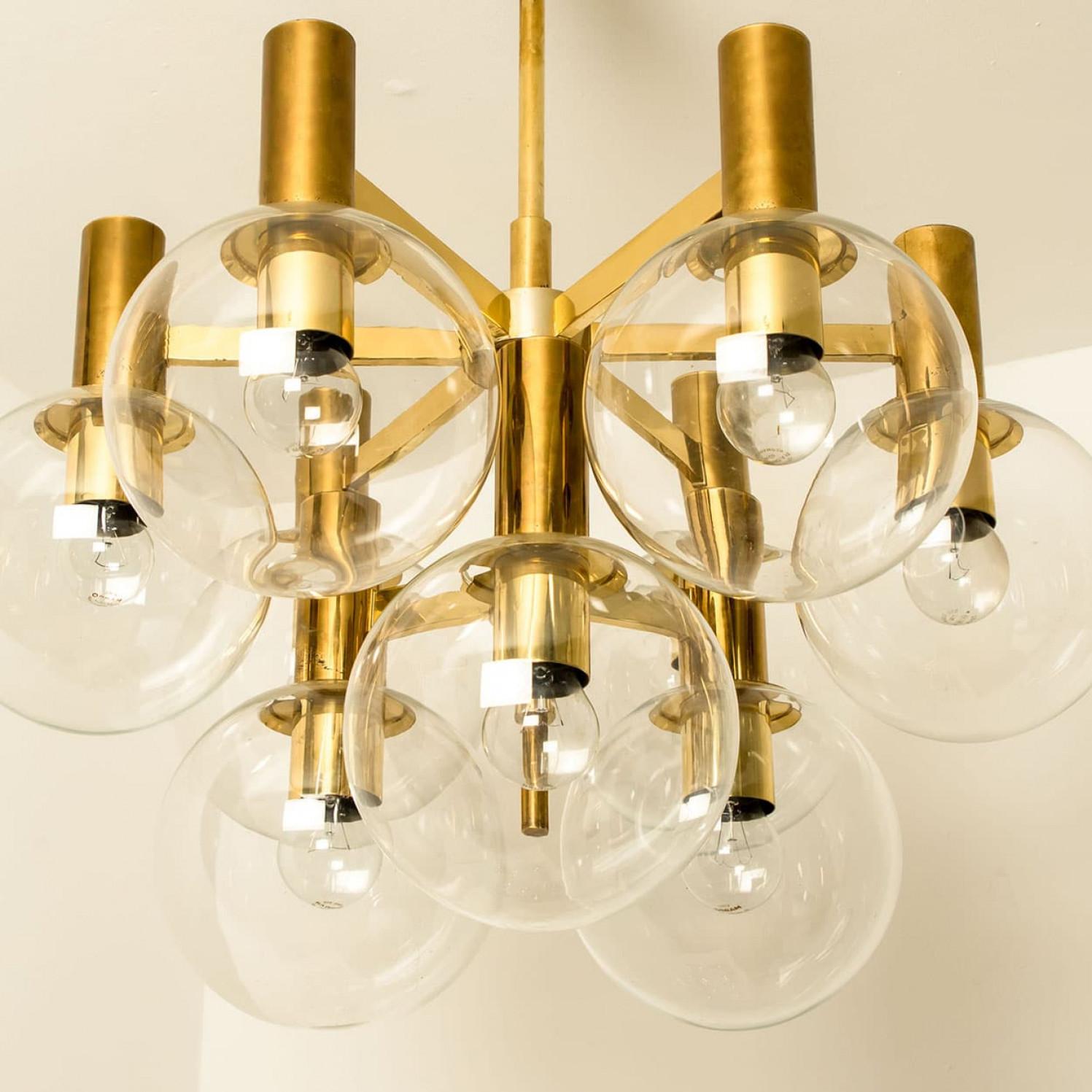 Wonderful chandelier with clear glass bowls and a brass base and fittings. Produced in the 1970s in the style of Hans-Agne Jakobsson. Illuminates beautifully.

Cleaned, well wired, in full working order and ready to use.
The lights can be