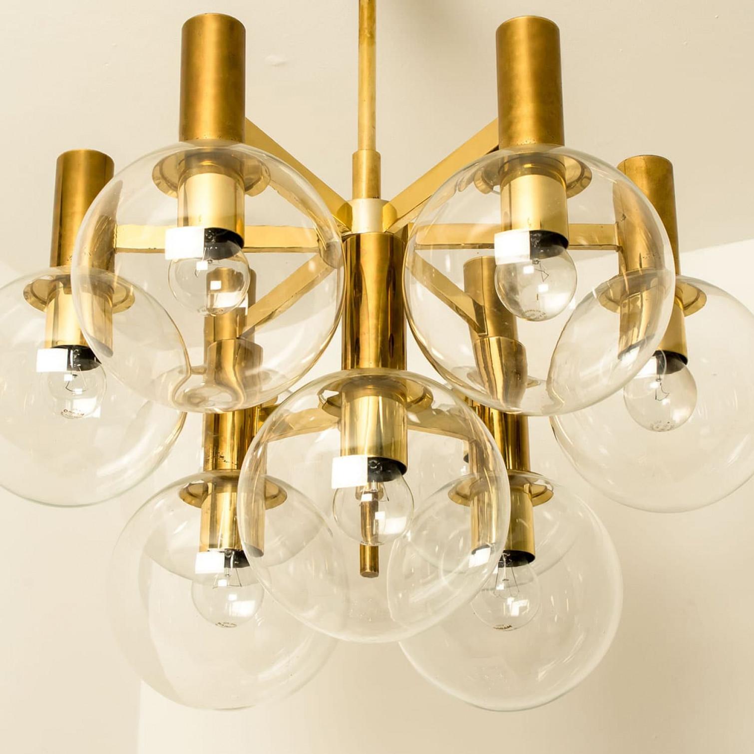 Wonderful chandelier with clear glass bowls and a brass base and fittings. Produced in the 1970s in the style of Hans-Agne Jakobsson. Illuminates beautifully.

Cleaned, well wired, in full working order and ready to use.
The lights can be