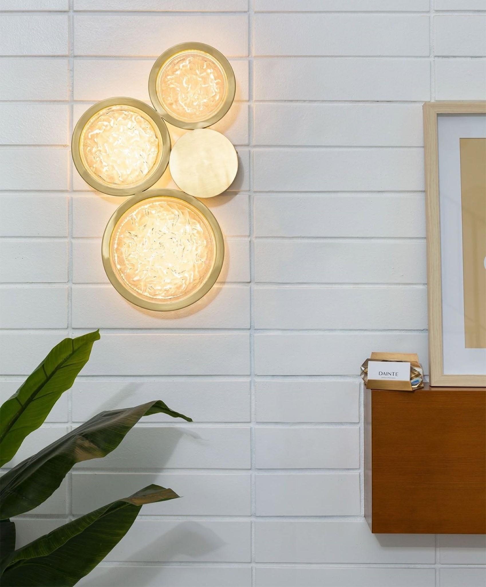 Add a touch of luxury and sophistication to your home with the Glass and Brass Circle Wall Sconce. Expertly crafted from high-quality brass and adorned with shimmering, textured glass circles, this sconce blends traditional elegance with modern