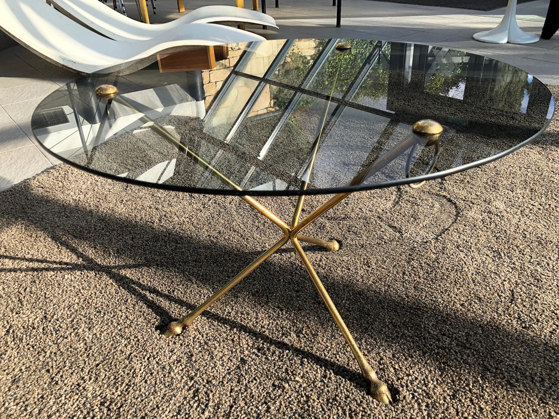 Round coffee table in smoked glass and brass, tripod legs in the form of clogs 1970, in the style of the house Jansen.