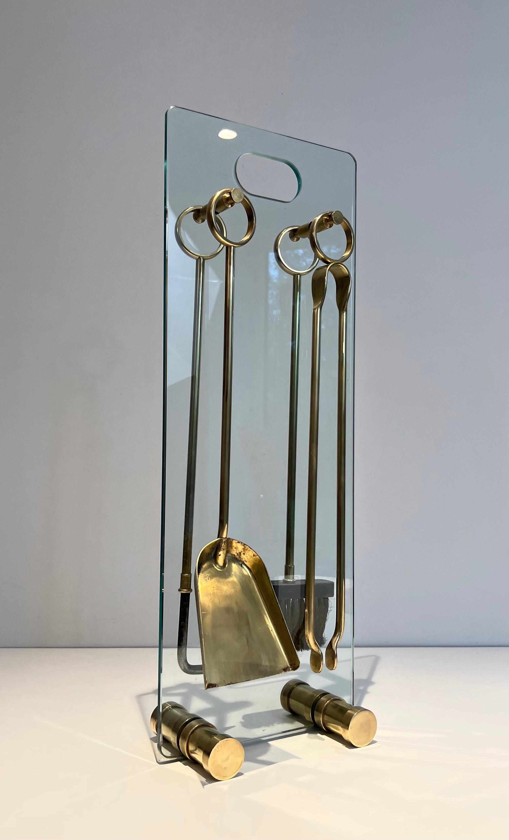 This design fireplace tools are made of brass on a glass stand with brass feet. This is a French work. Circa 1970.
