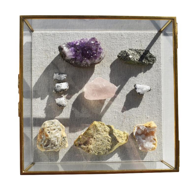 Beautiful square glass shadow box displaying an assortment of rocks and gemstones. A hinged glass lid opens to reveal a linen backed bottom and an assortment of gemstones and rocks. Each side is accented with brass, including the hinge. The rocks