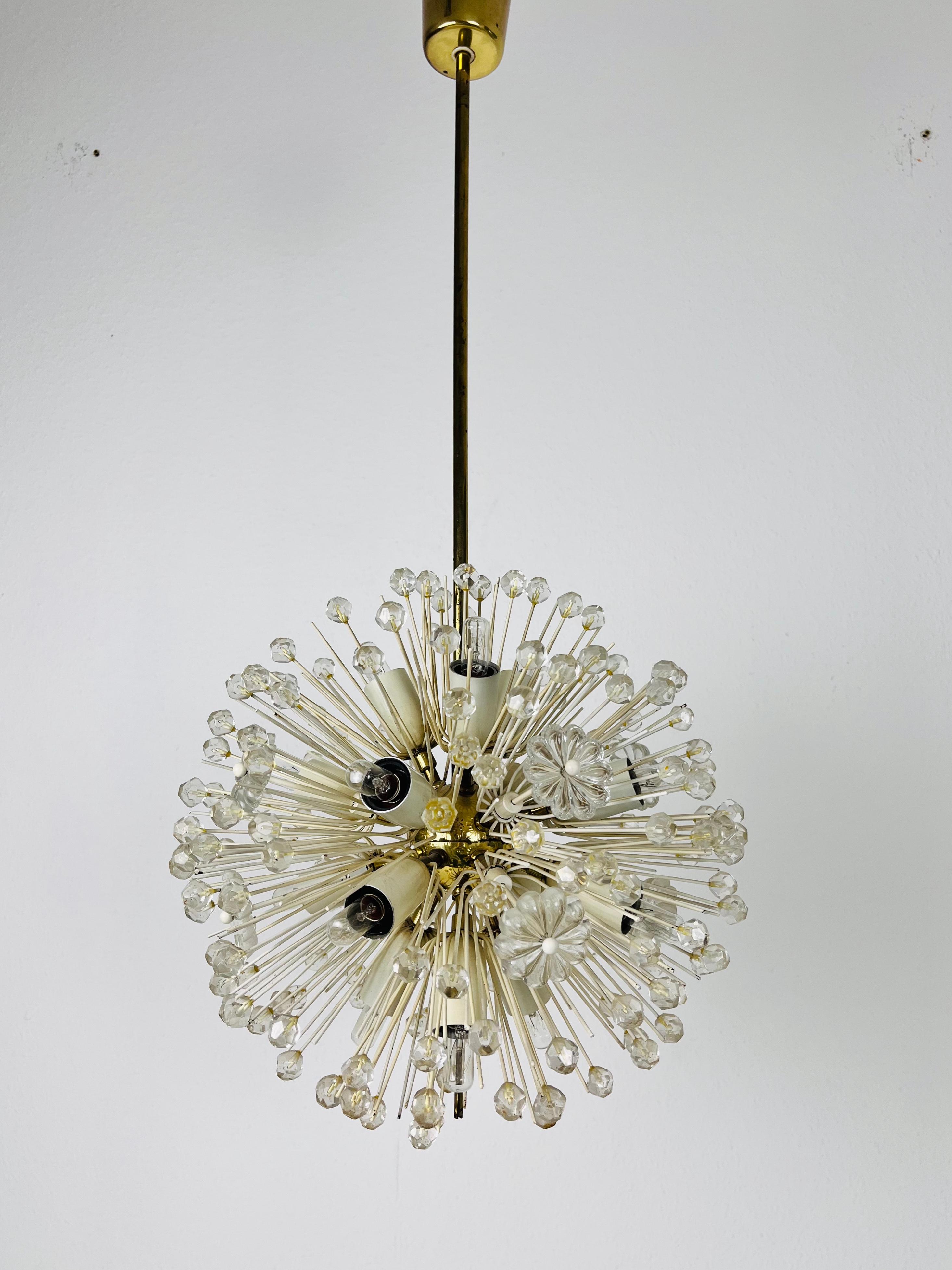 A beautiful chandelier made by Emil Stejnar for Rupert Nikoll, Austria in the 1960s. The lighting has an amazing midcentury design. It is made of brass and small glasses. The fixture has a very nice Hollywood Regency floral design.

The light