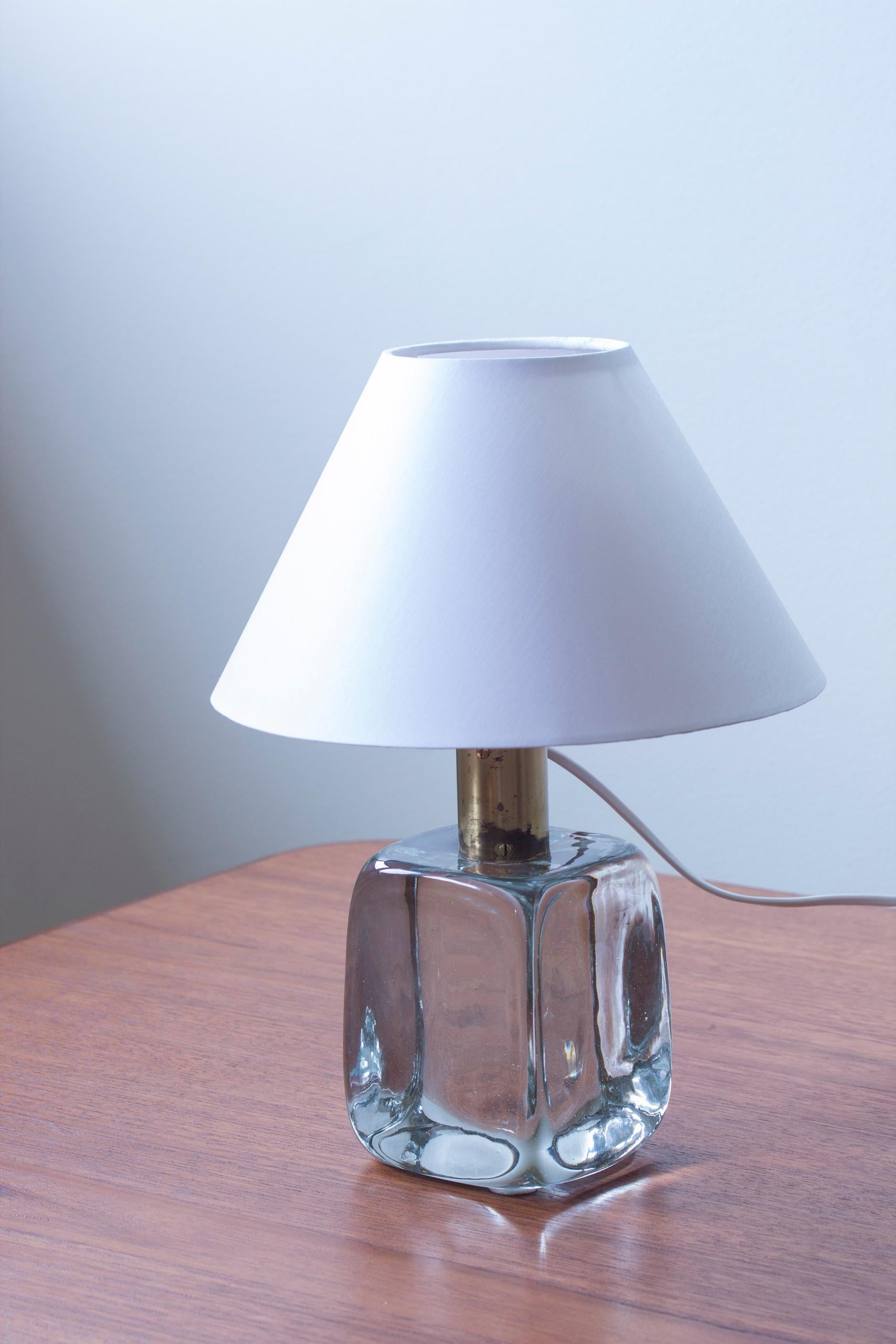 Table lamp model 1819 designed by Josef Frank in 1934. This piece produced by Firma Svenskt Tenn around the 1950-60s. Large mould blown clear glass square with brass top part and lamp socket. Light switch on the chord. New white chintz cotton lamp