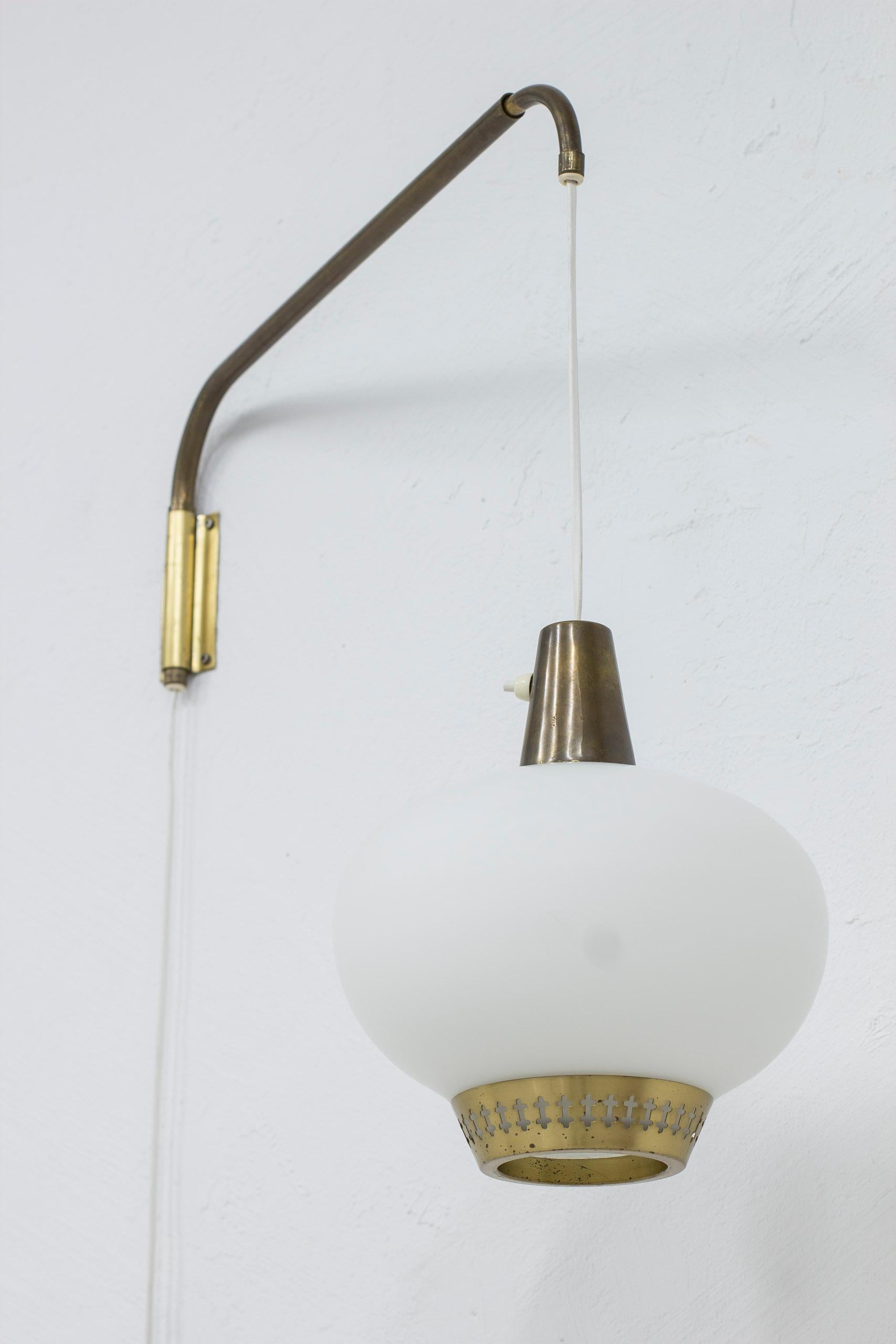 Rare wall lamp attributed to Hans Bergström. Produced by ASEA belysning during the 1950s. Brass lamp arm that easily adjusts and can be elongated. the chord can also be raised or lowered after preference. Lamp shade in opal glass with brass rim and
