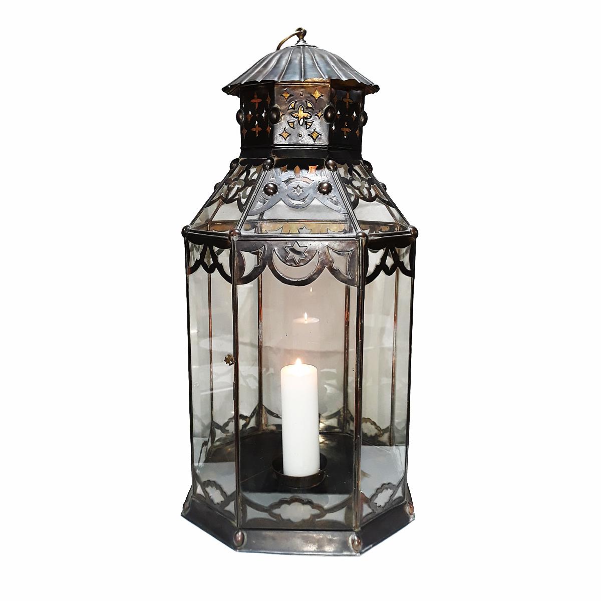 A tall lantern, handcrafted in Turkey. Made of metal and glass, with intricately carved details and candle holder in the center, for a 3-inch candle. Dimensions: 36