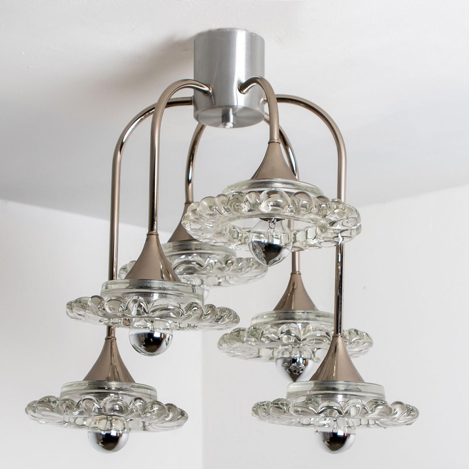 This sweet chandelier is made of thick clear glass and plated chrome. It is manufactured by Hillebrand, Germany around 1960.
The chandelier has six thick glass shades, hanging from a chrome plated base.

Measurements:
Diameter 16.54 inch (42cm) x