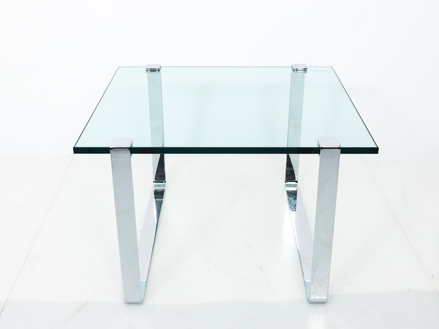 Glass top century modern side table in the style of Milo Baughman with chrome bracket base in a polished finish, circa 20th century.