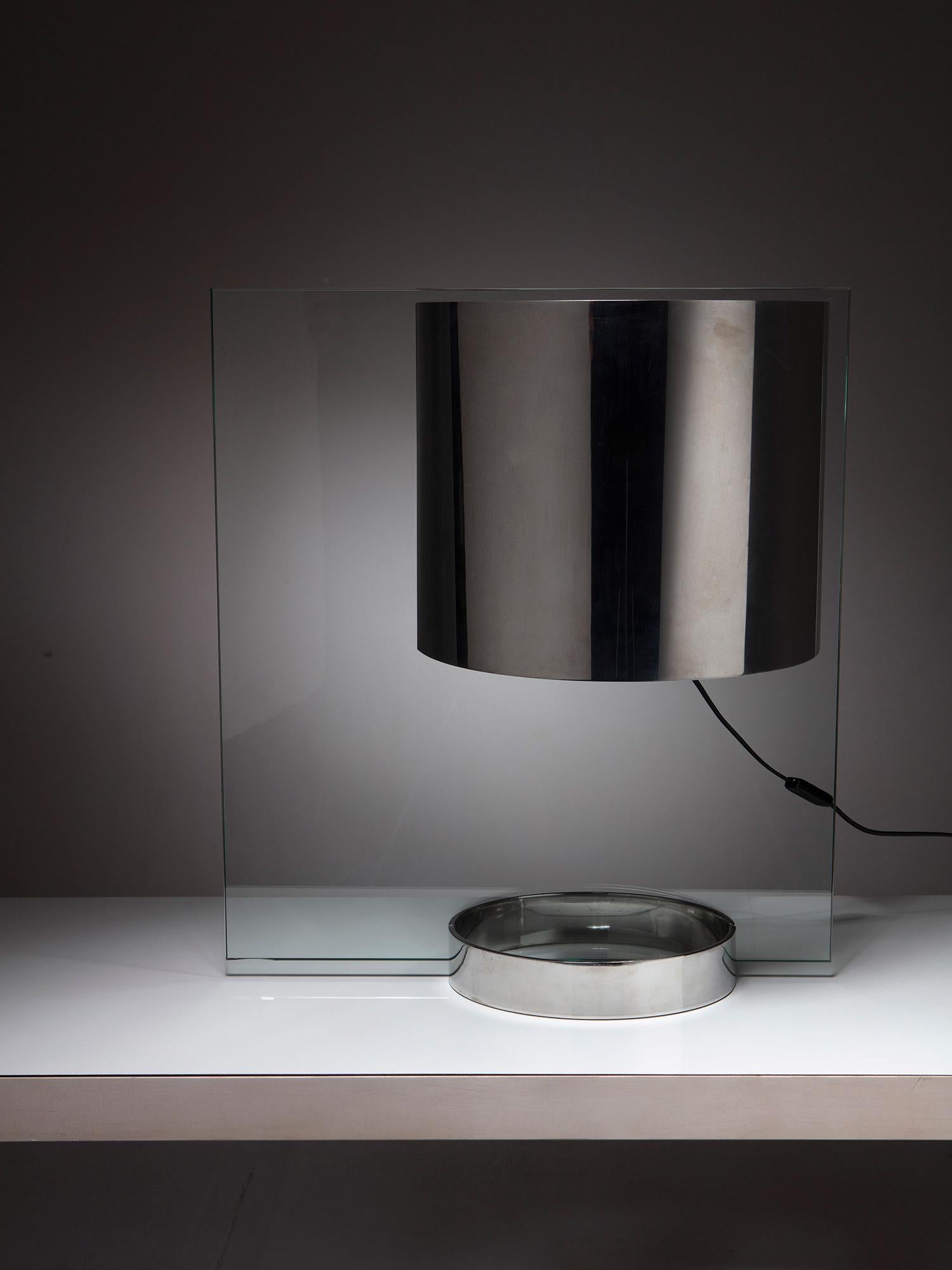 Große Tischleuchte von Ennio Chiggio für Lumenform.
Ein dickes Glaselement trägt einen verchromten Schirm und einen Metallsockel.
Das Licht schwebt visuell auf der Oberfläche.