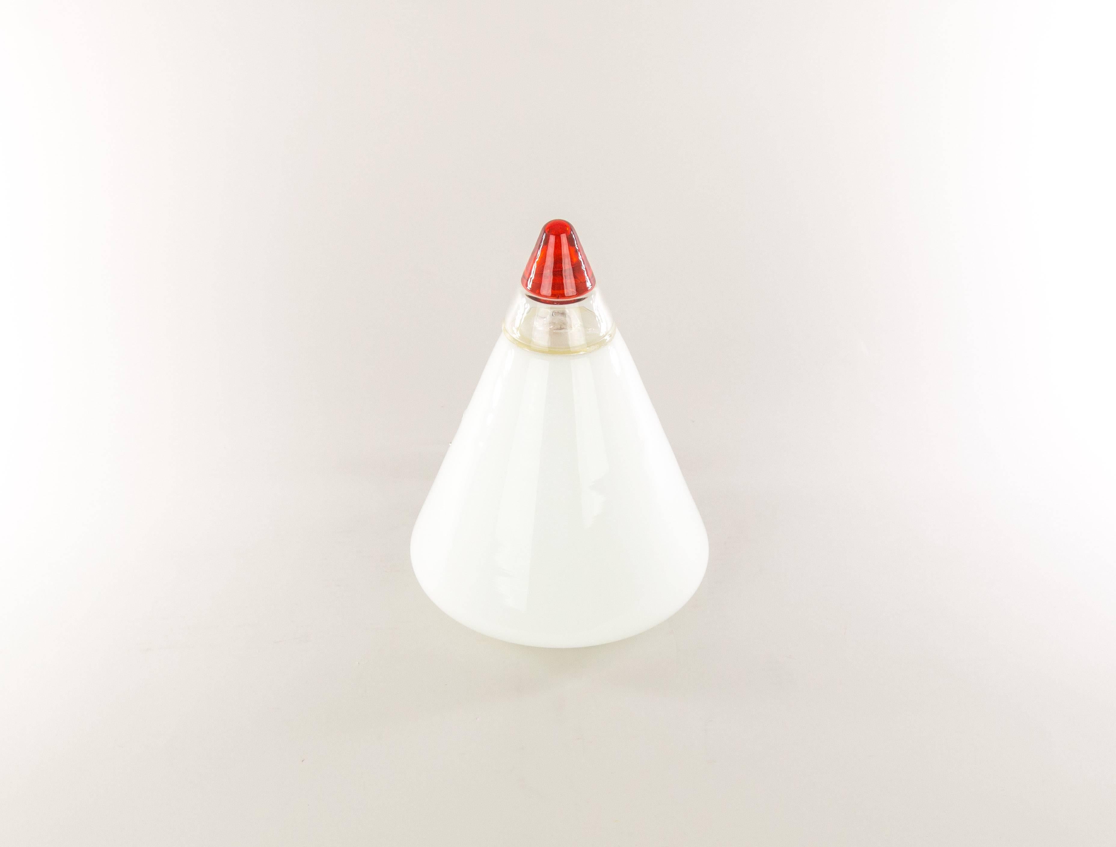 Rio table lamp designed by Giusto Toso for Italian manufacturer Leucos.

The cone-shaped lamp is made of hand blown white and red glass and has a crystal band as a decoration.

The glass part is supported by a white plastic base that is marked