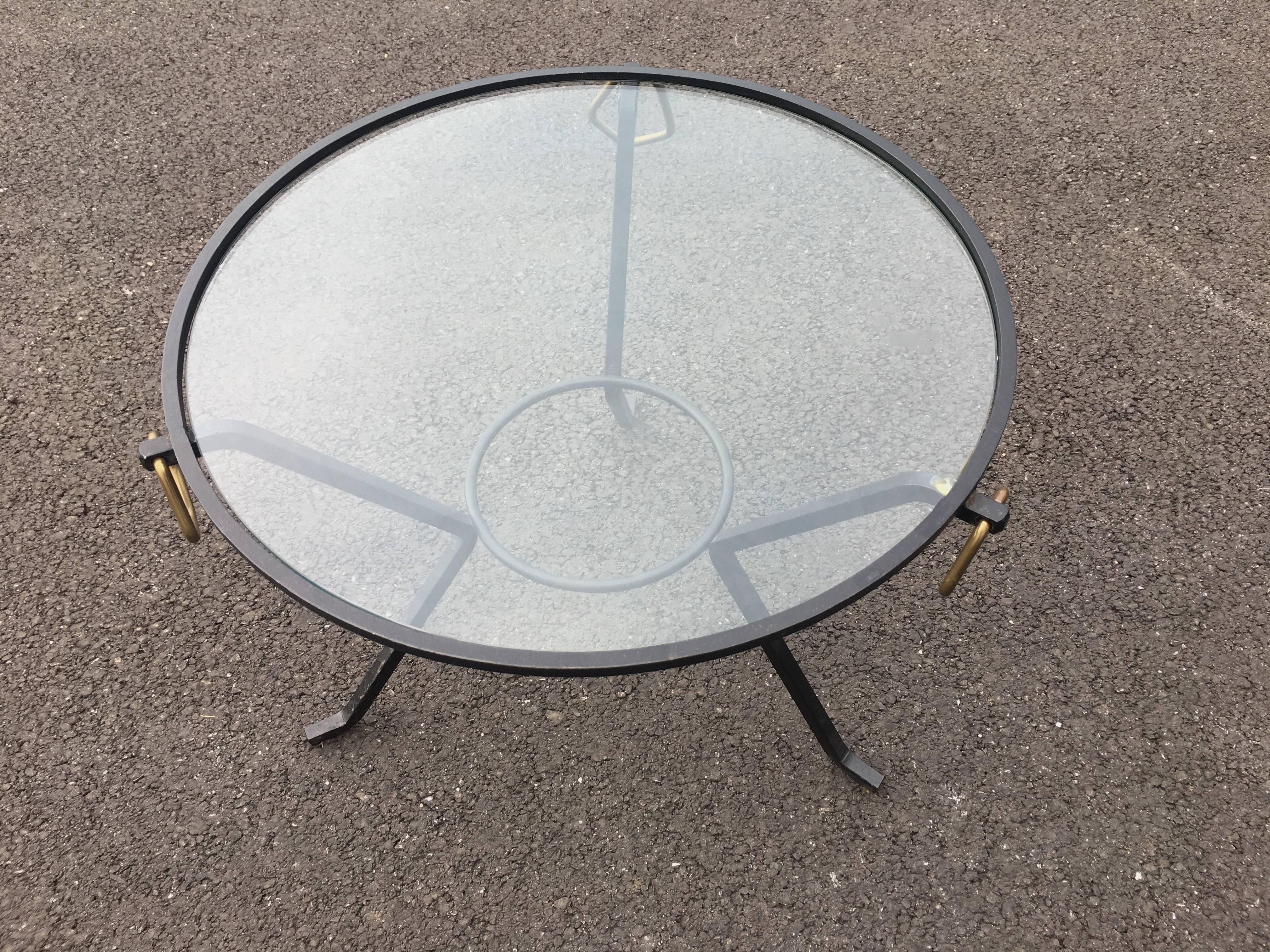 Circular table with a metal base, brass loops and clear glass top from the 1950s.