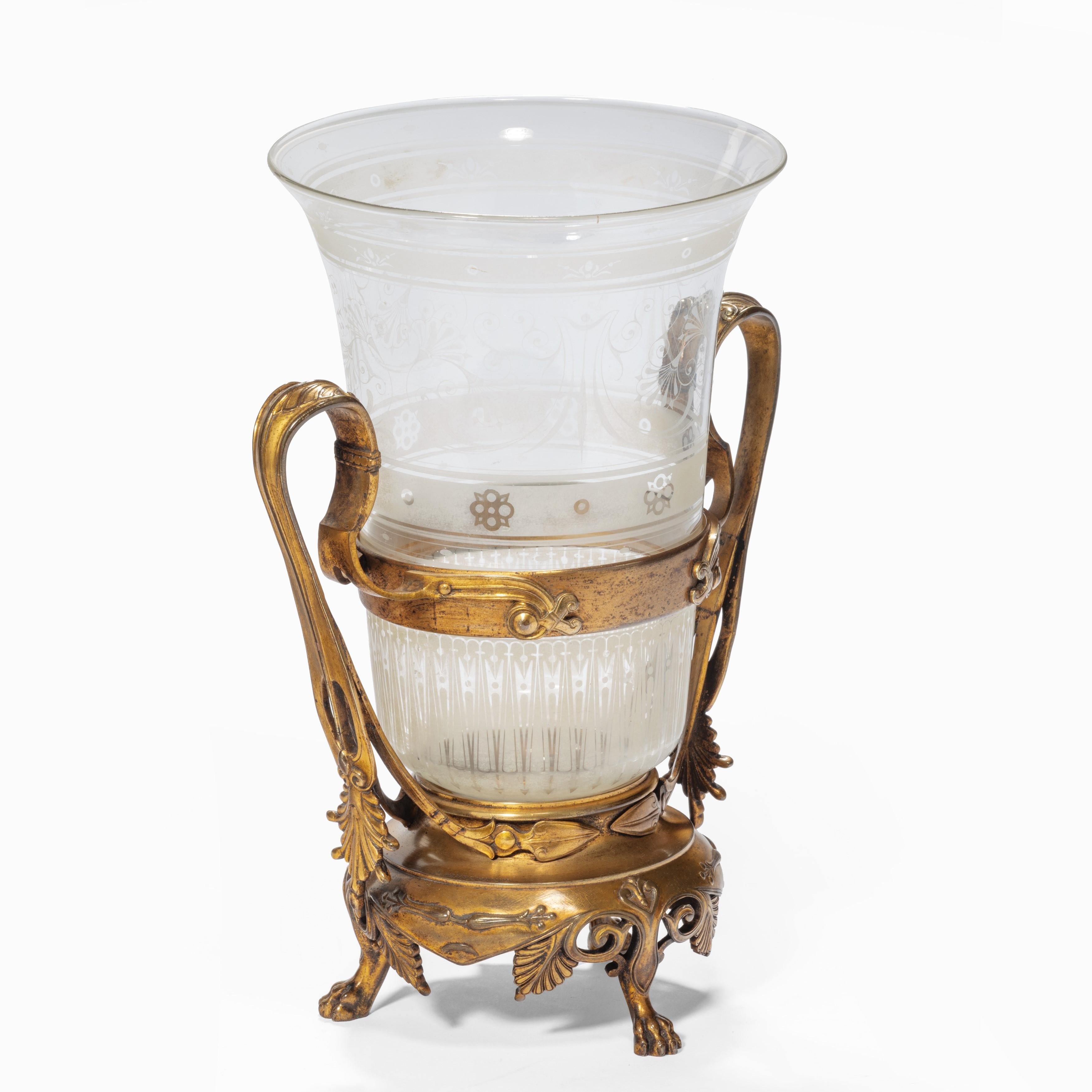 A glass and ormolu vase by the Barbedienne foundry, the flared glass beaker decorated with bands of acid etched stylized floral motifs and lanceolate leaves, the bronze holder with a pair of arched strap handles on a shaped base with three lion’s