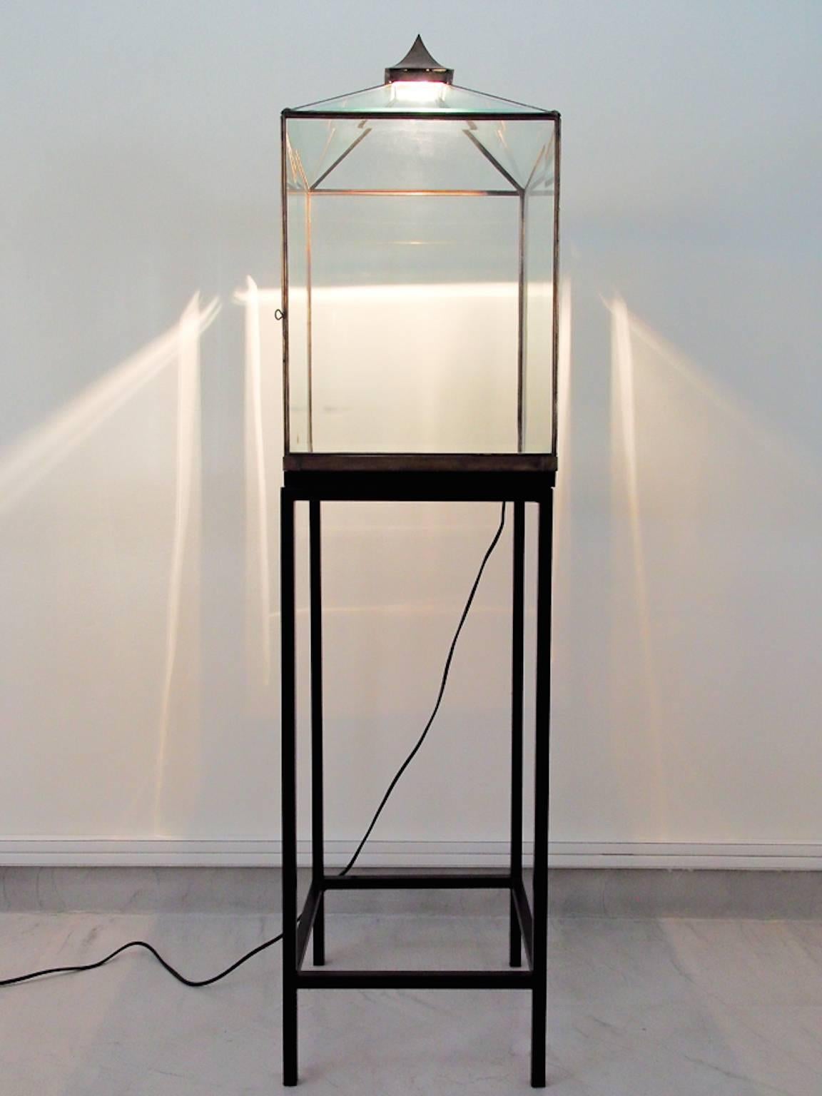 Unique Balinese style floor light/display stand. Glass top with oxidized metal frame and black painted metal stand. Glass top with a door and space to display artwork or other items.