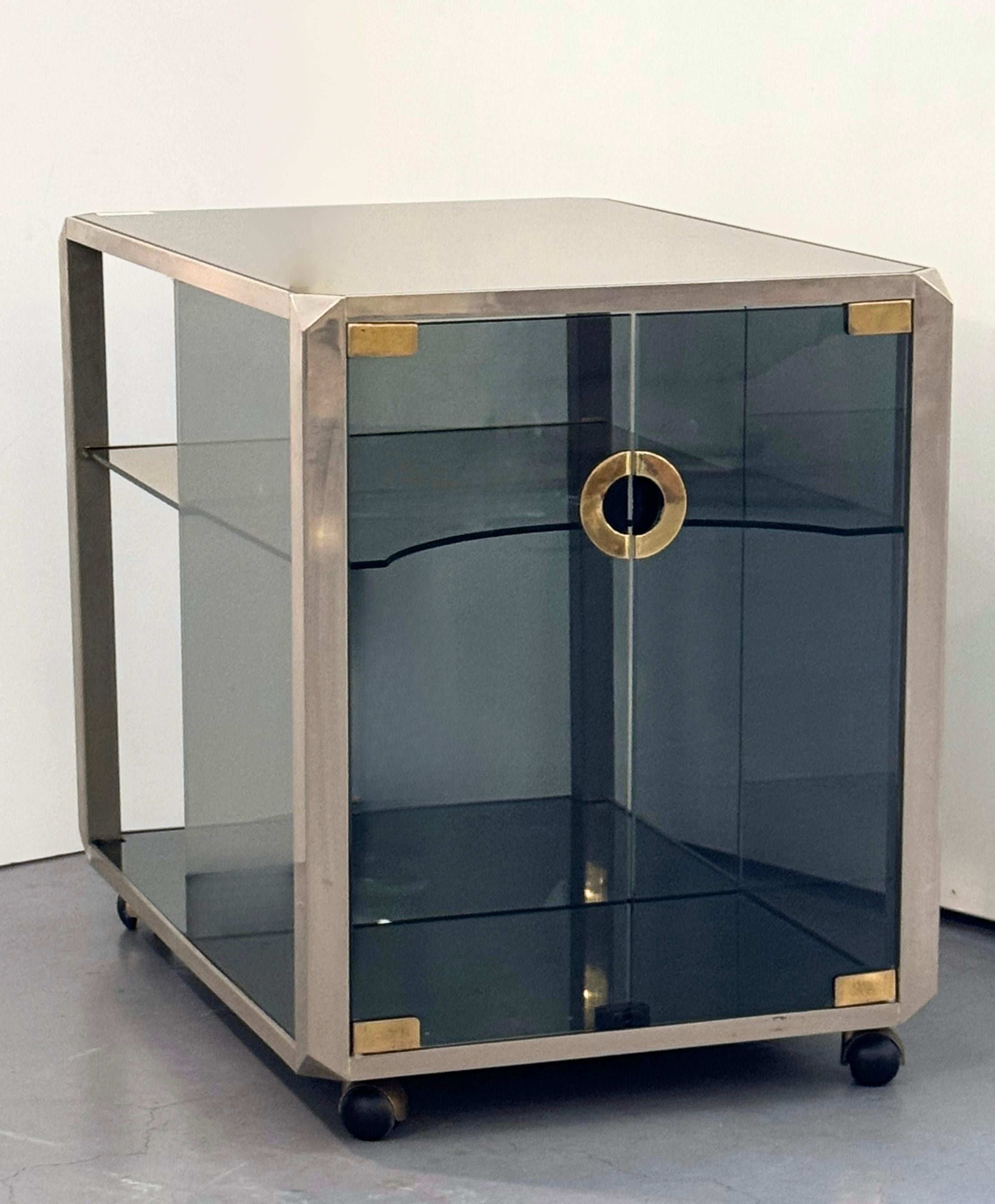 Mid-Century design polished steel and smoked glass bar cart cabinet by Willy Rizzo for Mario Sabot, circa 1970s.
Polished steel frame with glass walls and internal glass shelves. 
Including 1 extending shelf with brass trimmed edge.
Signature Rizzo