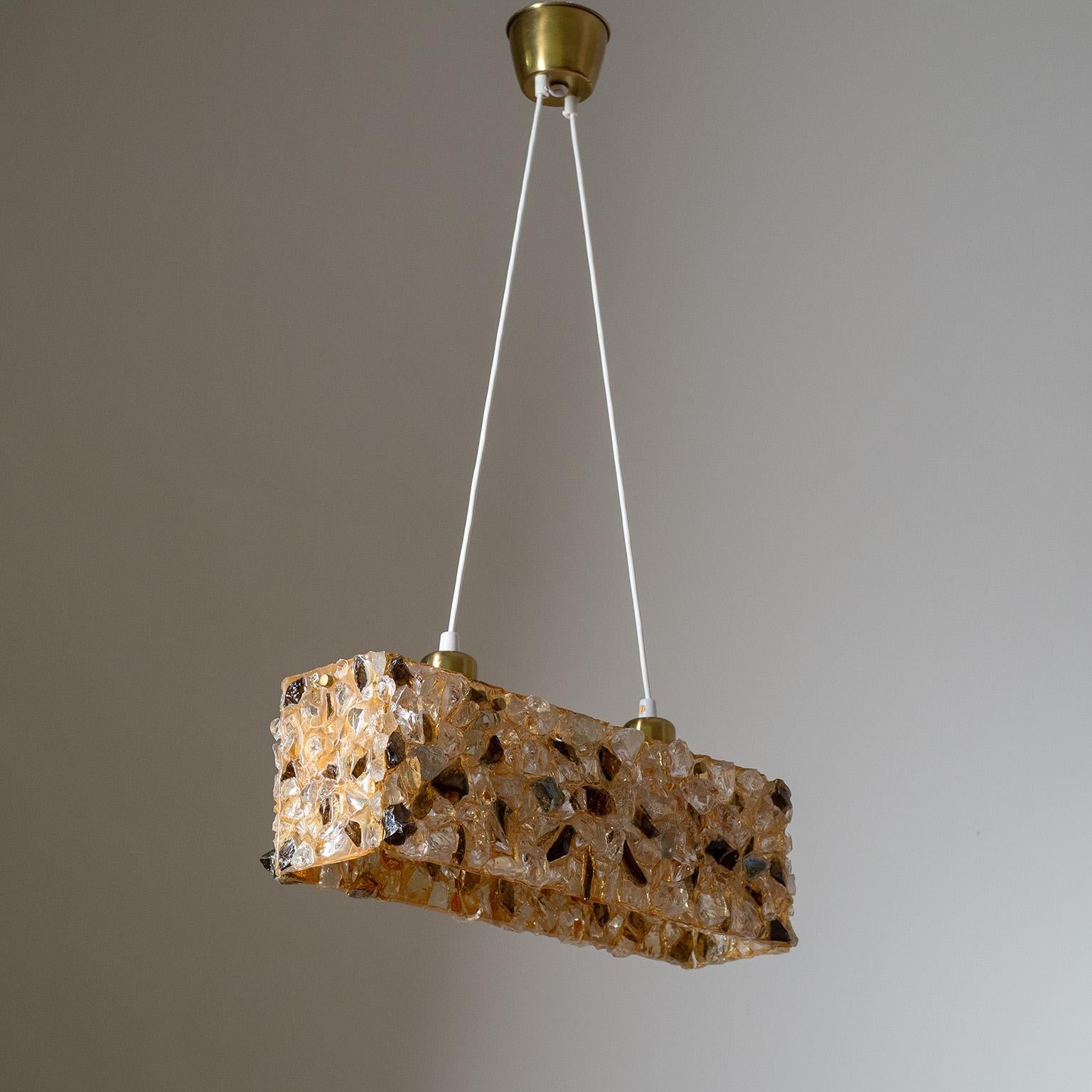 Fine Brutalist glass and resin suspension light from the 1960-1970s. Chunks of clear and tinted glass shards are embedded into an amber colored resin body and suspended by two wires leading to two original brass E27 sockets with new wiring.